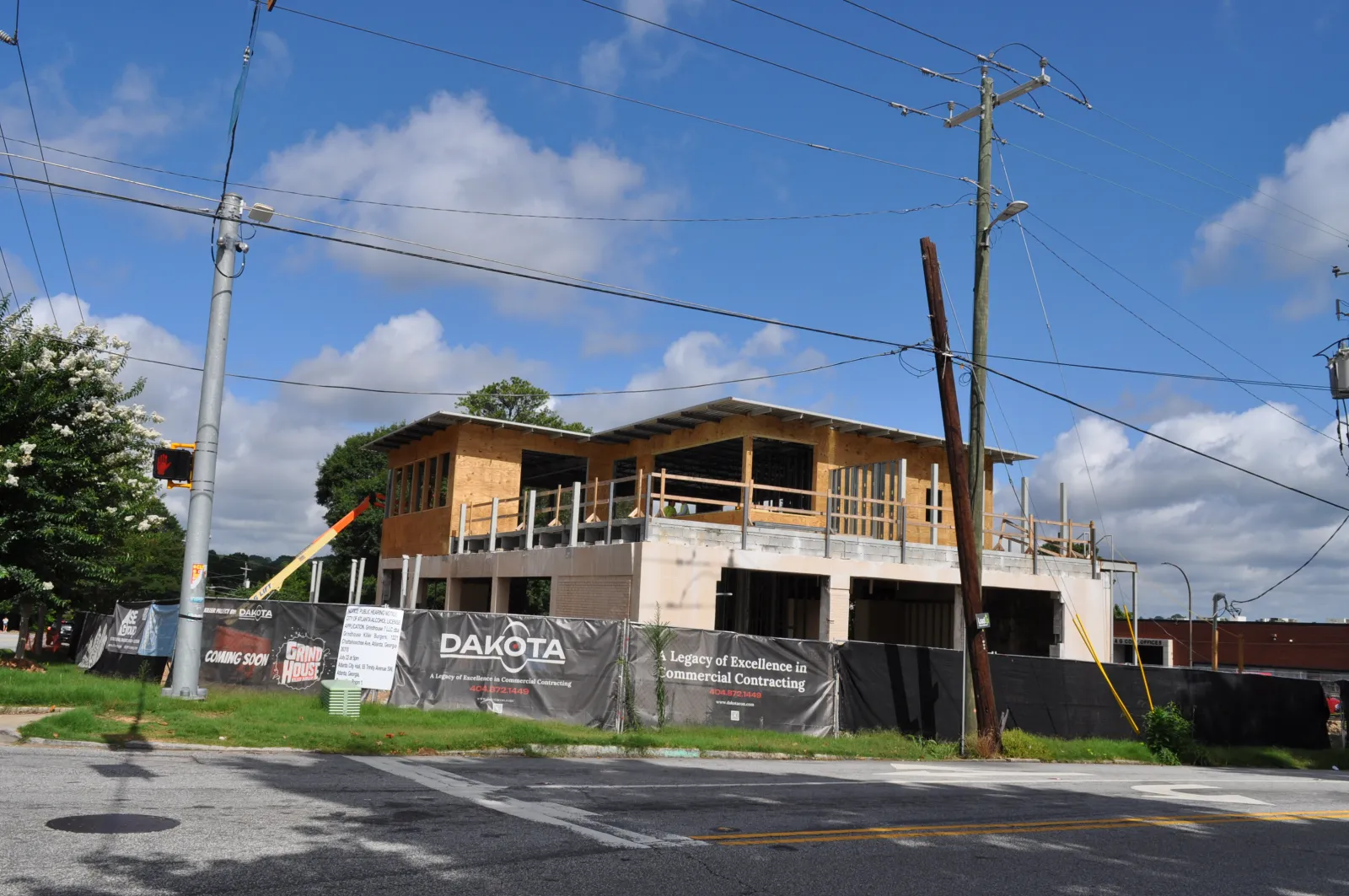 Commercial building under construction with wooden framing and safety barriers on a sunny day.