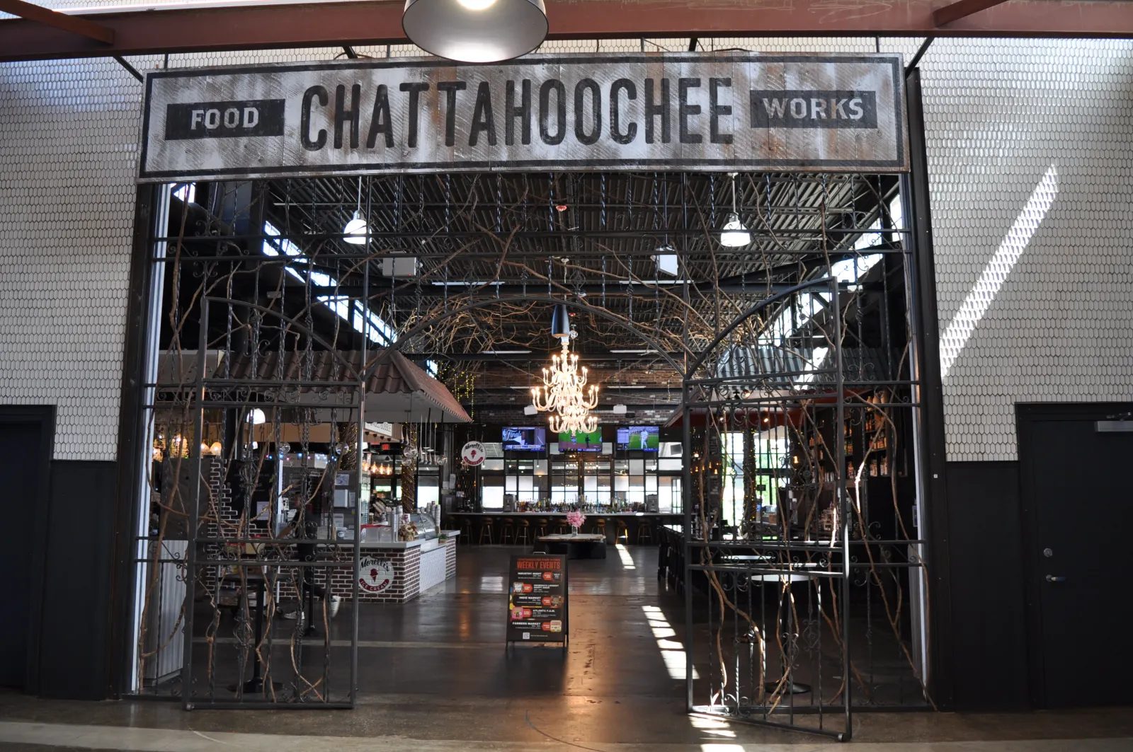 Entrance to Chattahoochee Food Works with metal gate, chandelier, and open dining area inside.