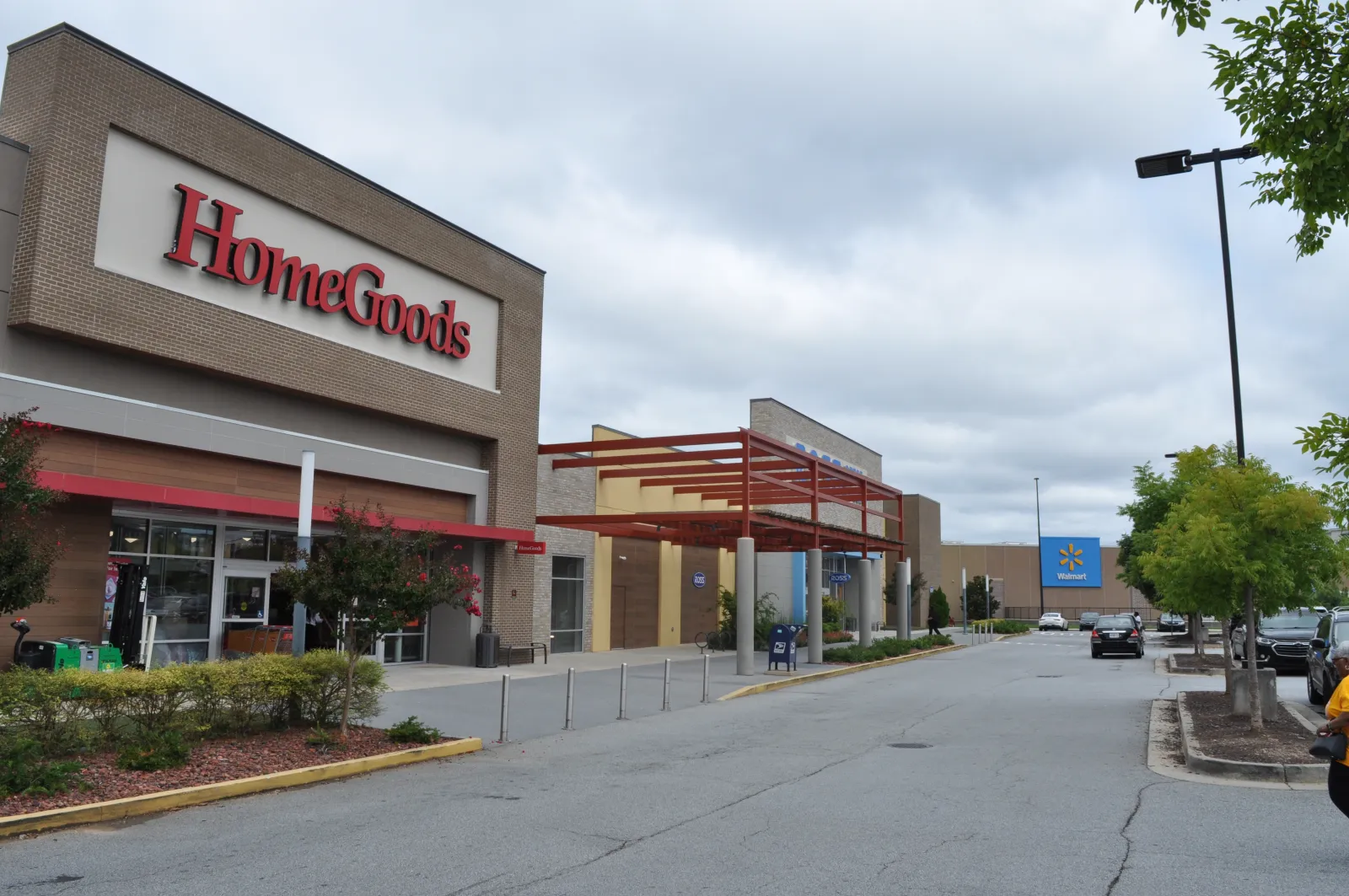 Exterior view of HomeGoods store next to Walmart in a shopping plaza under a cloudy sky.