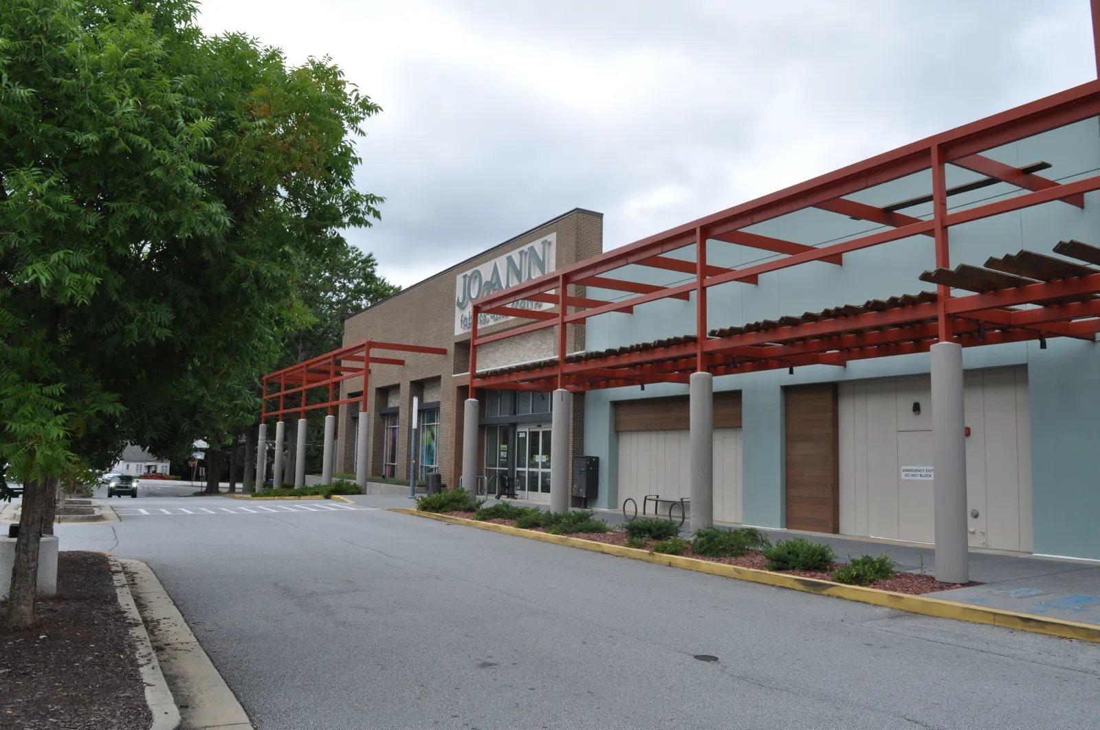Empty street view of a Jo-Ann fabric and craft store with red pergola and overcast sky