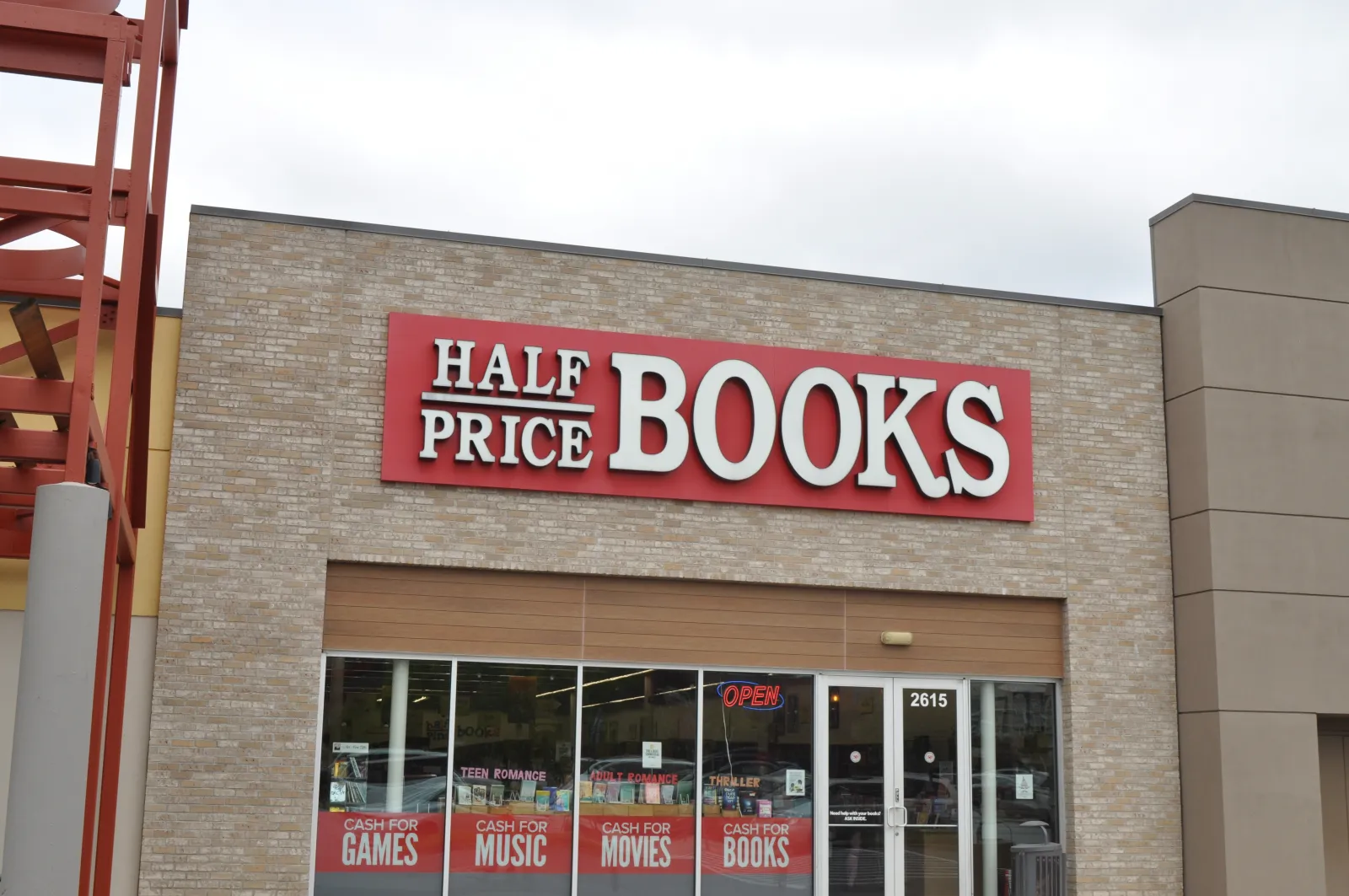 Exterior of Half Price Books store with signage advertising cash for games, music, movies, and books.