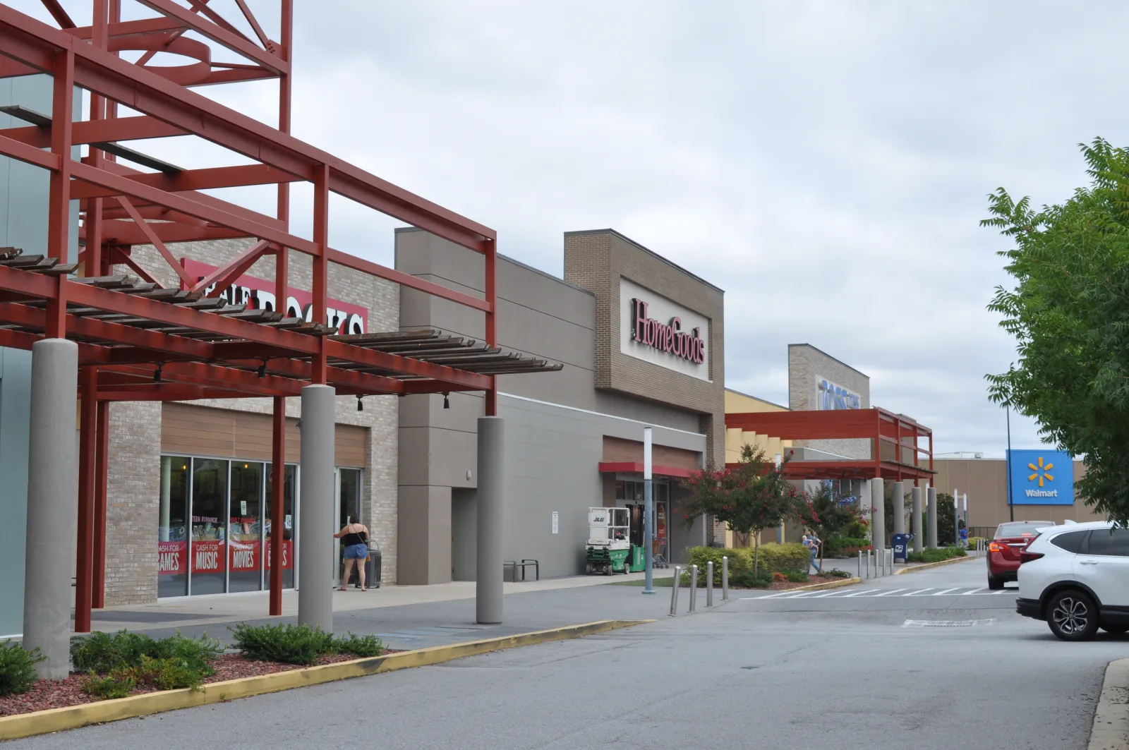Shopping center exterior with HomeGoods and Walmart stores under a cloudy sky with parked cars.
