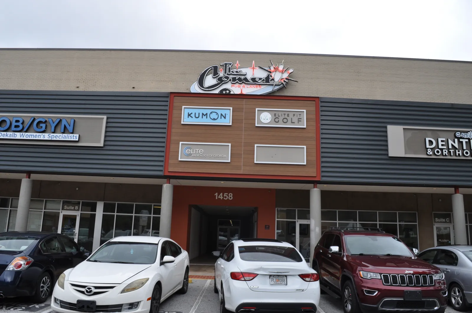 Front view of a commercial building with parked cars and signs for Kumon, Elite Golf, OB/GYN, and dental offices.