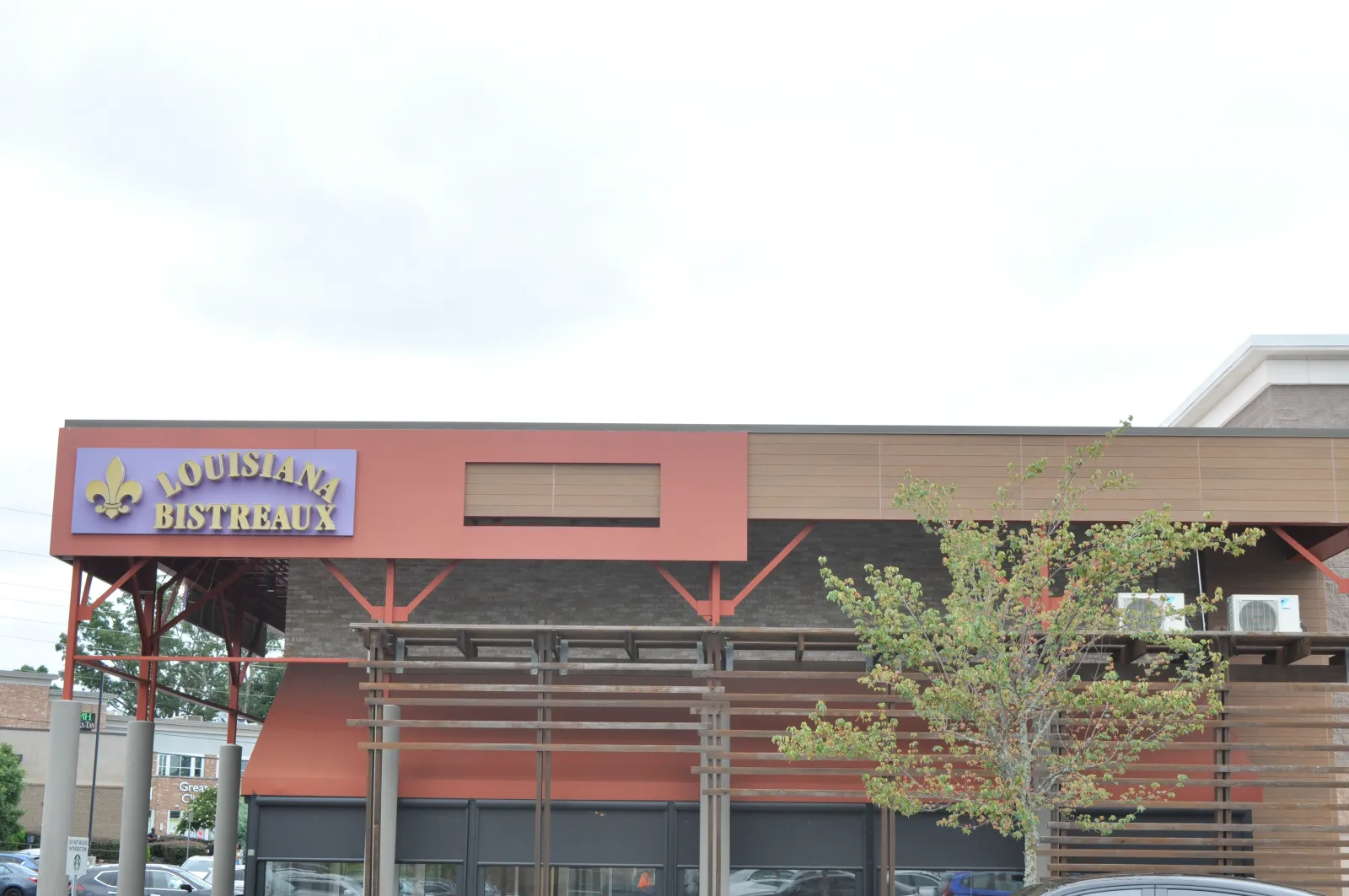 Louisiana Bistreaux restaurant exterior with sign, orange awnings, wooden pergola, and a tree in front.