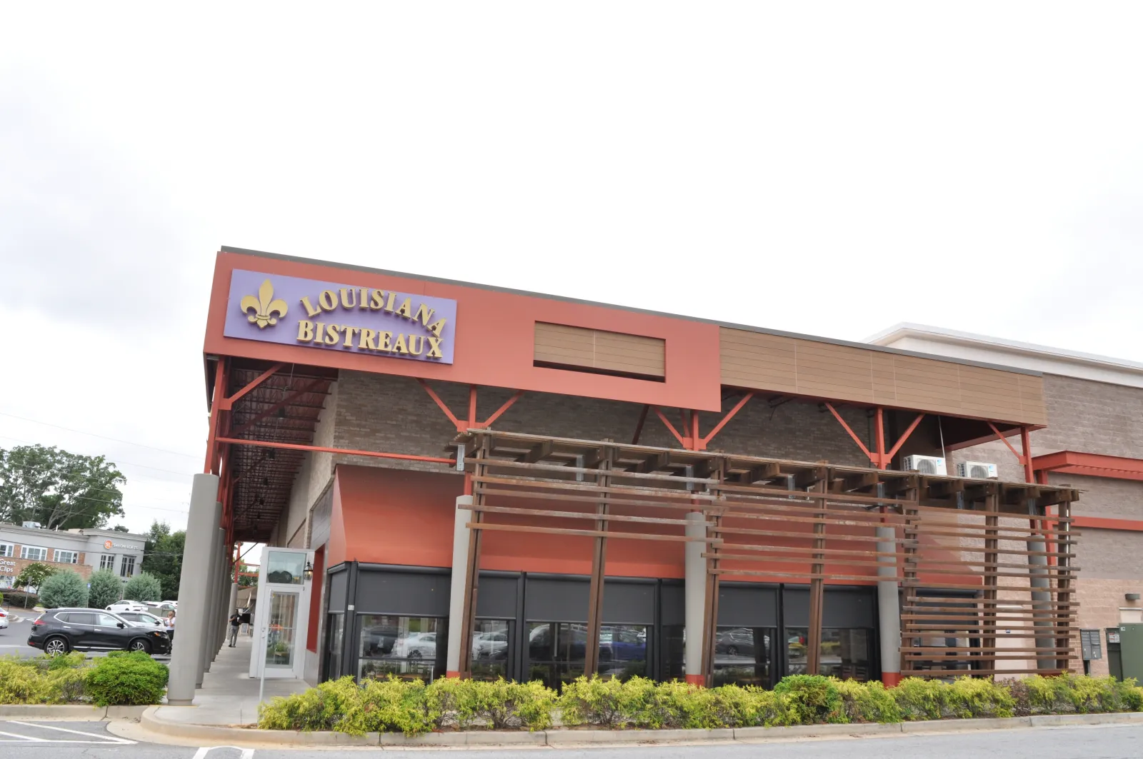 Exterior view of Louisiana Bistreaux restaurant with red and brown facade and wooden pergola structure.