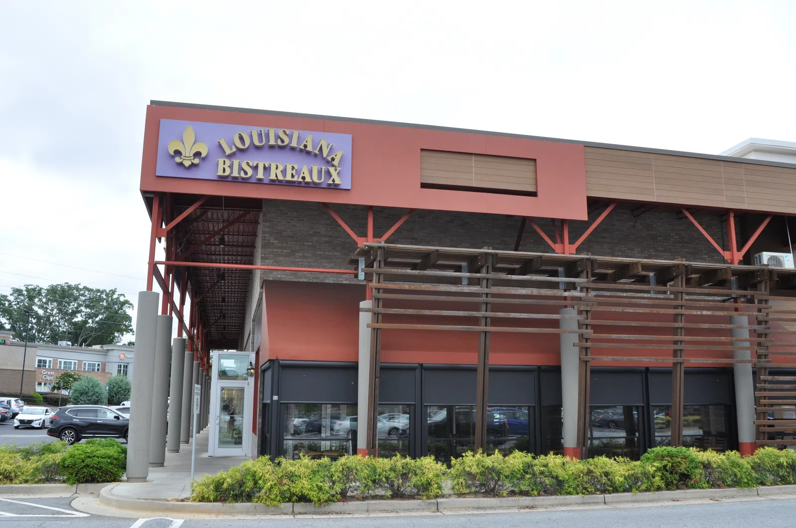 Exterior view of Louisiana Bistreaux restaurant with red and brown facade and parking lot in front