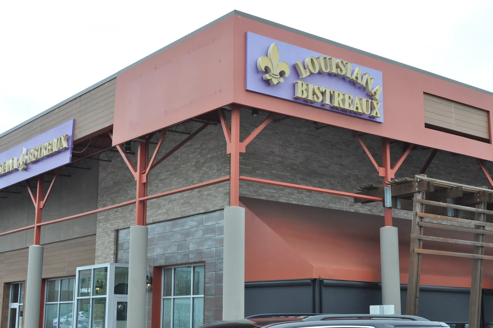 Exterior view of Louisiana Bistreaux restaurant with purple and gold signage on a building corner.