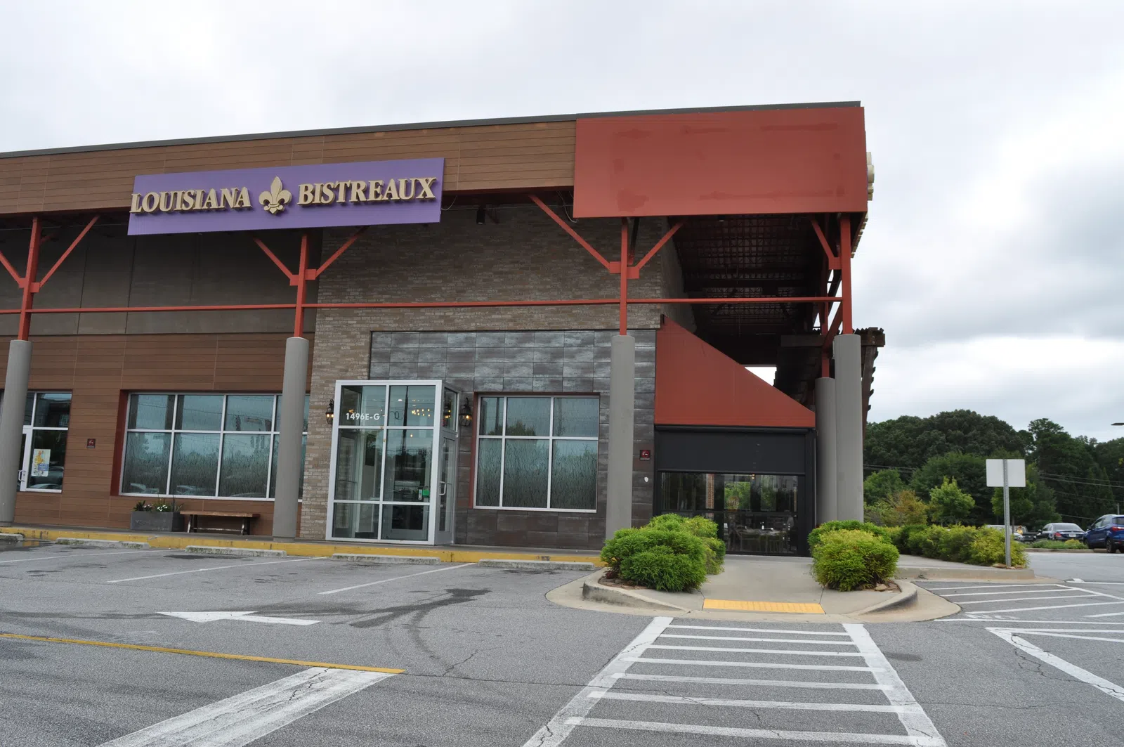 Exterior view of Louisiana Bistreaux restaurant with parking lot and greenery on a cloudy day