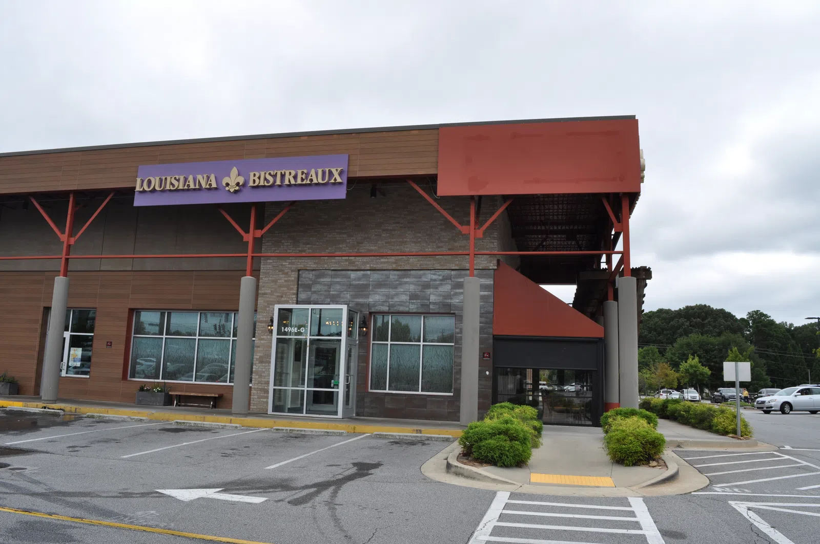 Exterior view of Louisiana Bistreaux restaurant with parking lot and cloudy sky background