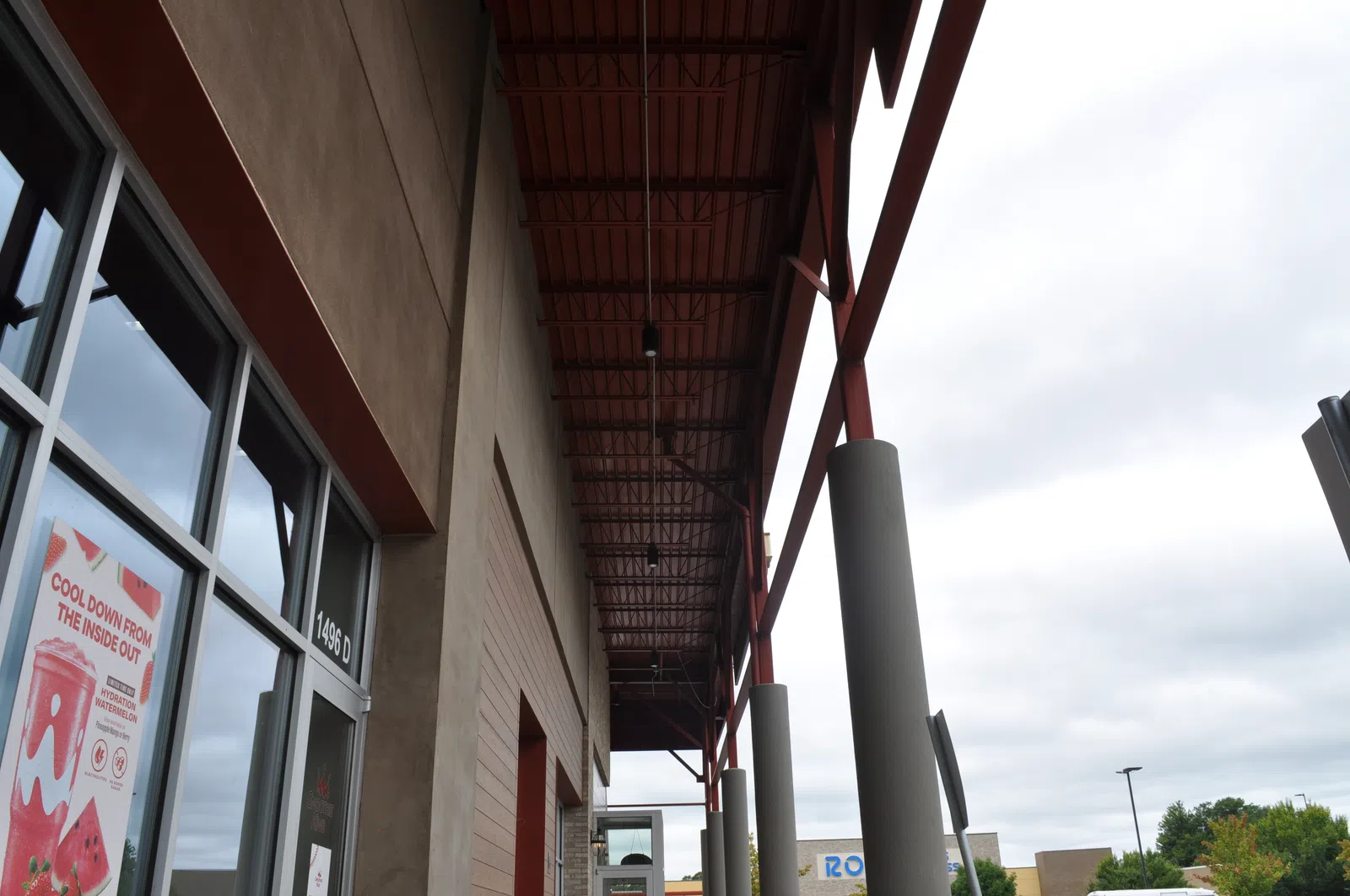 Exterior view of a commercial building entrance with tall pillars and cloudy sky in the background.