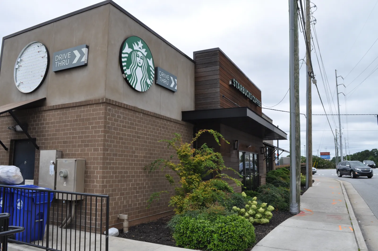 Exterior view of a Starbucks coffee shop with drive-thru signs on a cloudy day.