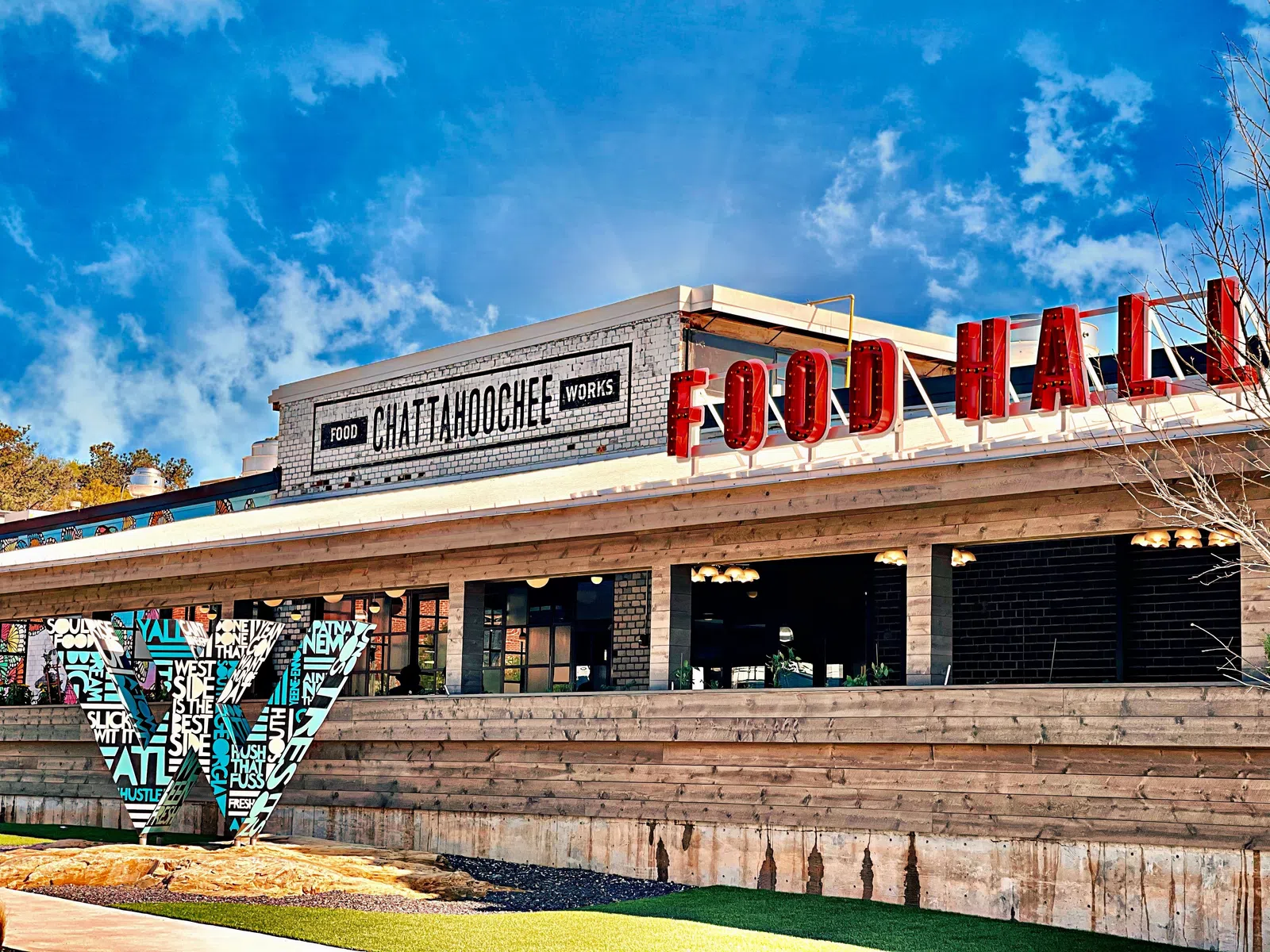Chattahoochee Food Works building with red Food Hall sign under a bright blue sky.