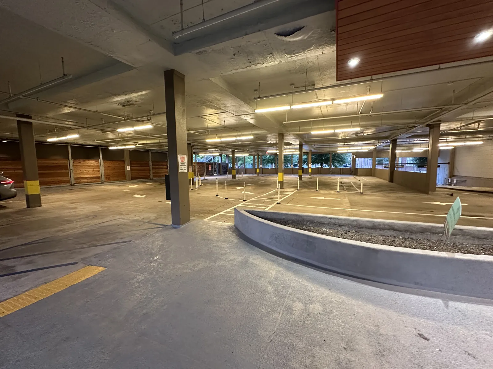 Empty indoor parking garage with concrete pillars, yellow markings, and overhead fluorescent lights