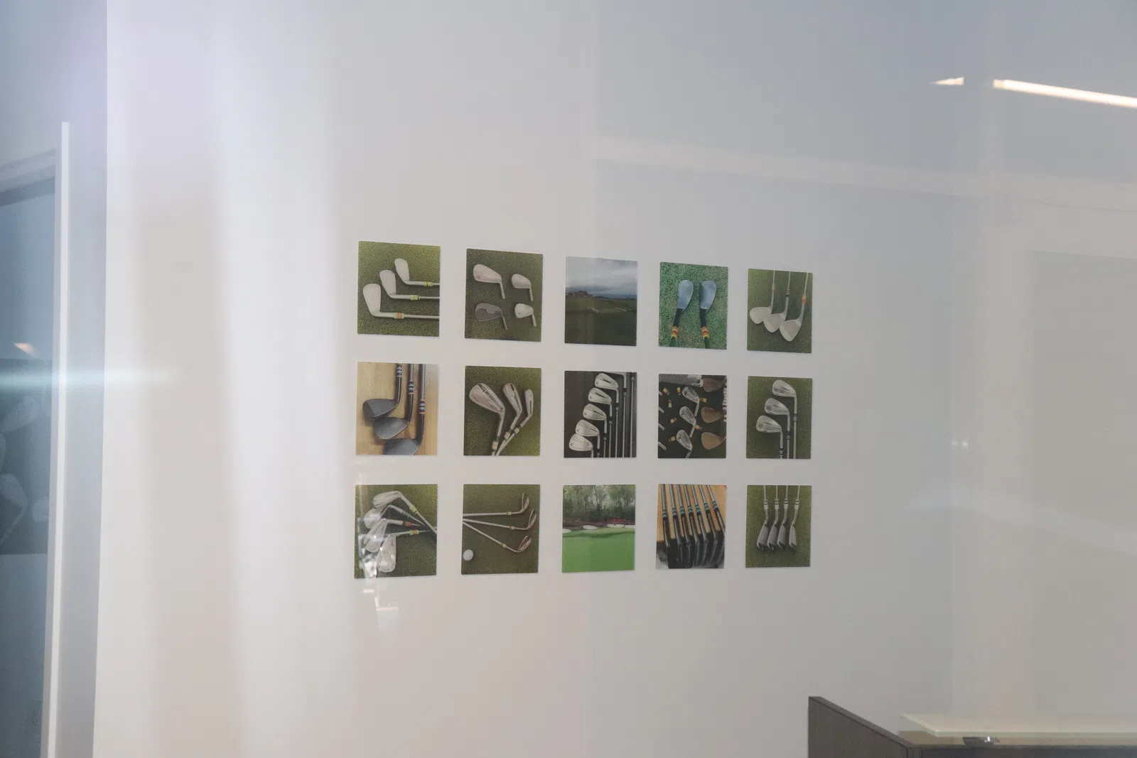 Wall display of sixteen small framed photos showing various golf clubs and golf shots in a modern indoor space.