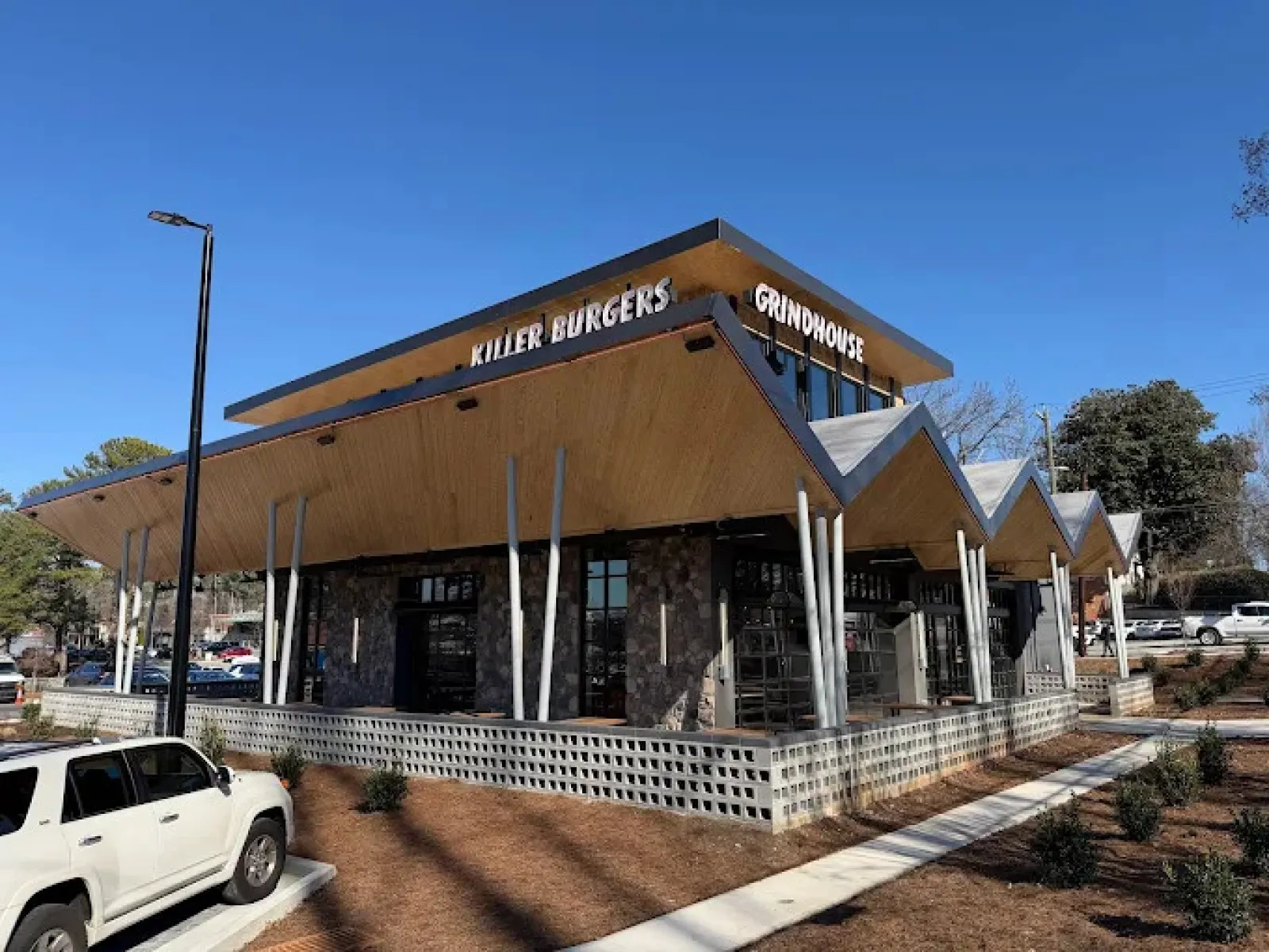 Modern restaurant building with unique angled roof and signage for Killer Burgers and Grindhouse on sunny day.