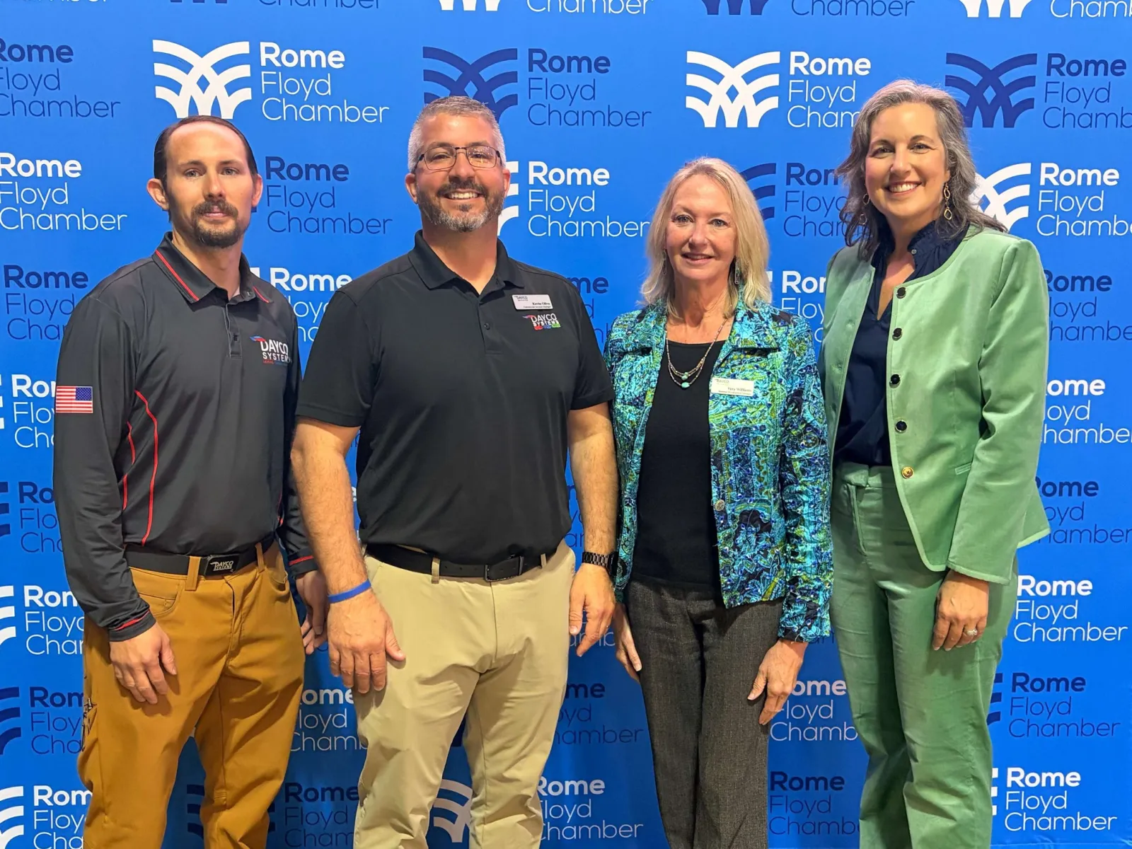 Four professionals standing in front of Rome Floyd Chamber backdrop during an event or meeting.