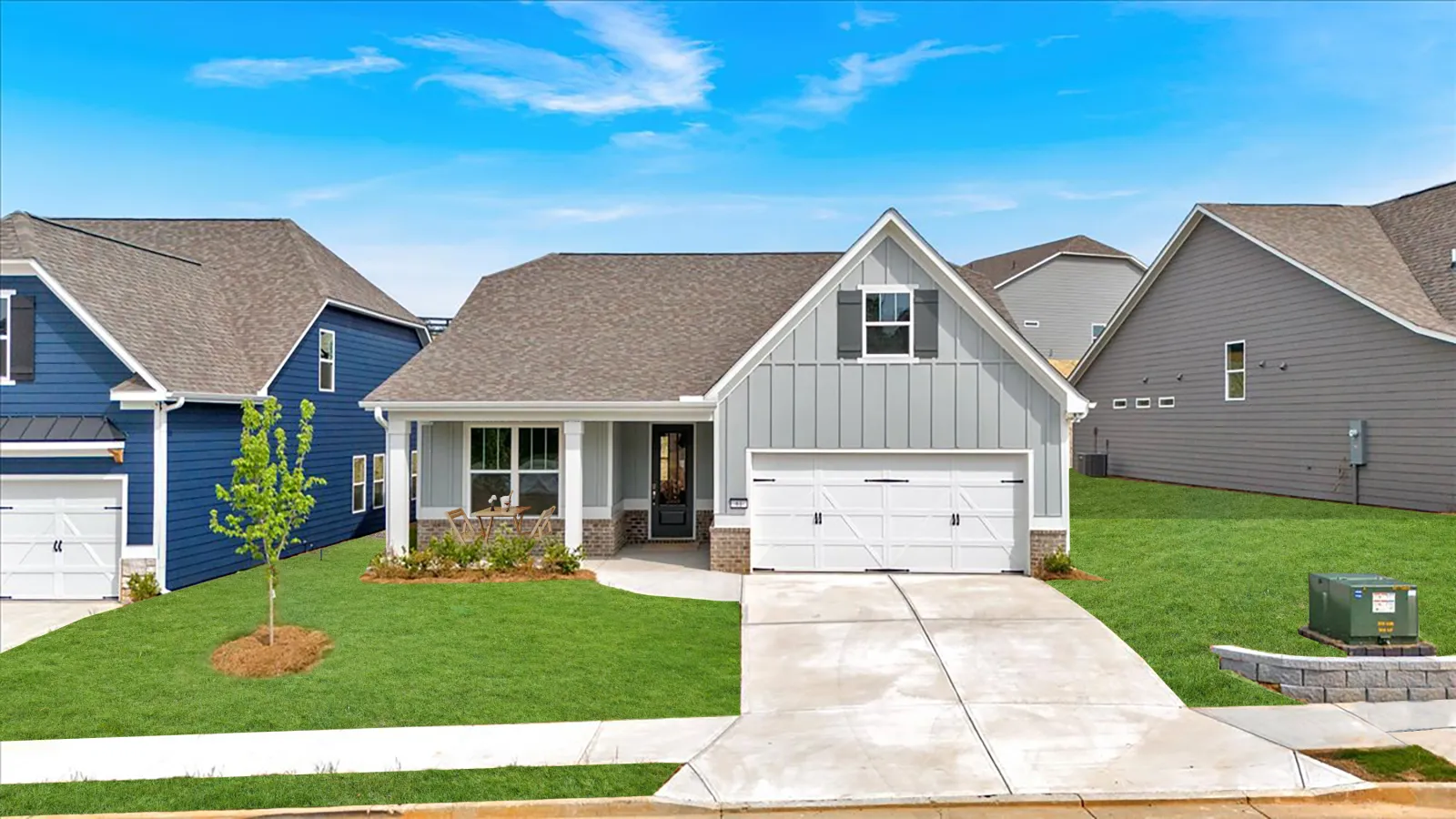 Modern single-family house with gray siding, white garage door, and neatly landscaped green lawn under a blue sky