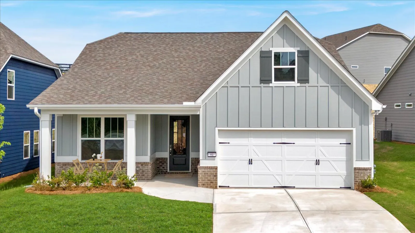 Modern single-story gray house with white garage door, front porch, and green lawn under blue sky