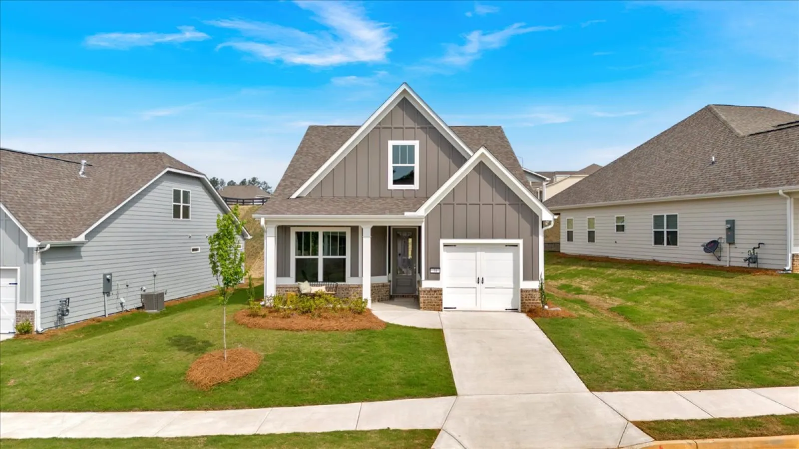 Modern single-family home with gray siding, white trim, and a one-car garage on a sunny day.