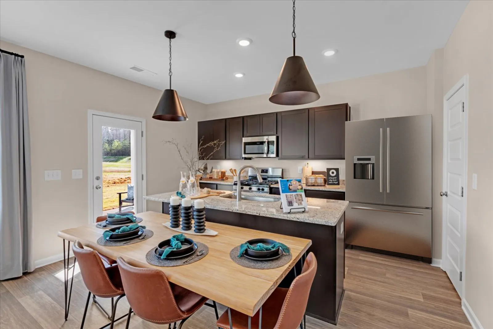 Modern kitchen with wooden dining table, black cabinetry, and stylish pendant lighting, showcasing sleek appliances.