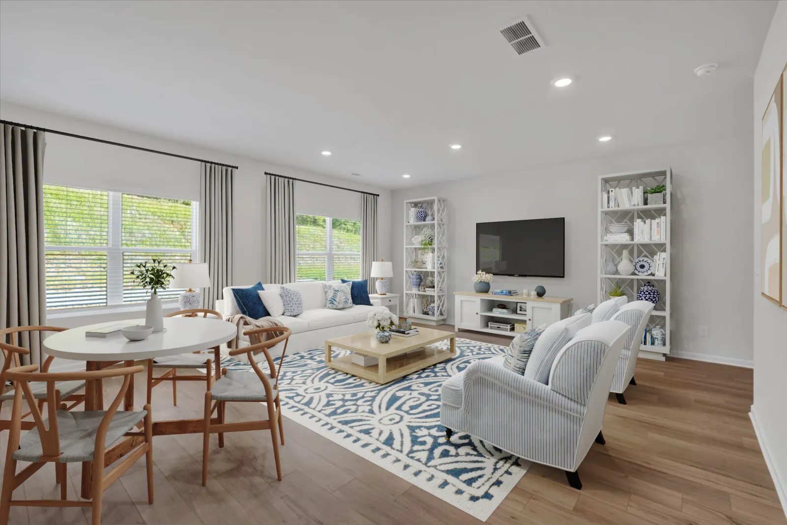 Bright modern living room with white furniture, blue patterned rug, wooden dining set, and large windows with curtains.