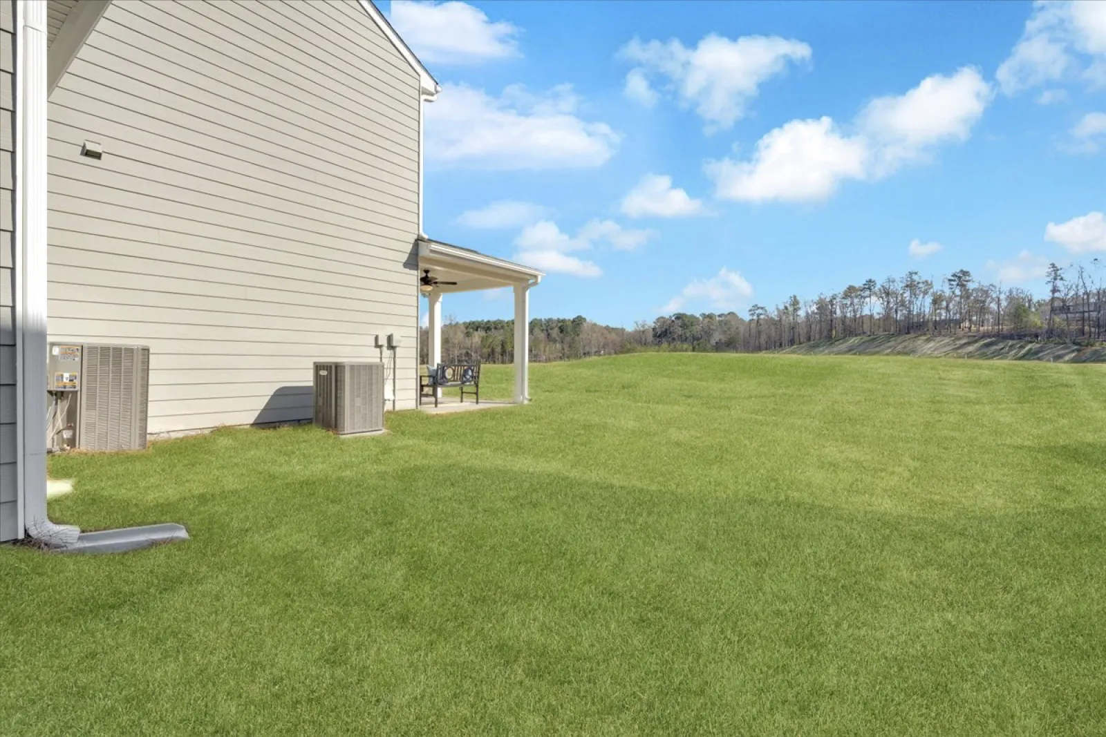 View of a home exterior with a grassy yard and clear blue sky in the background.