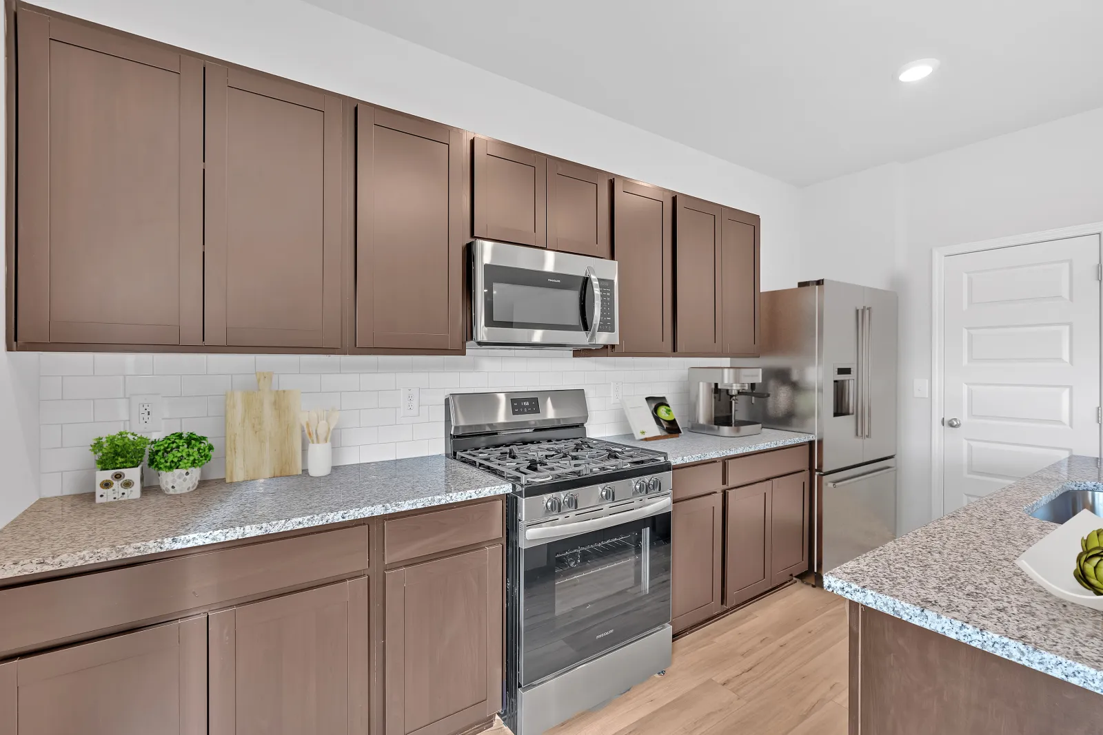 Modern kitchen featuring brown cabinets, stainless steel appliances, and a granite countertop.