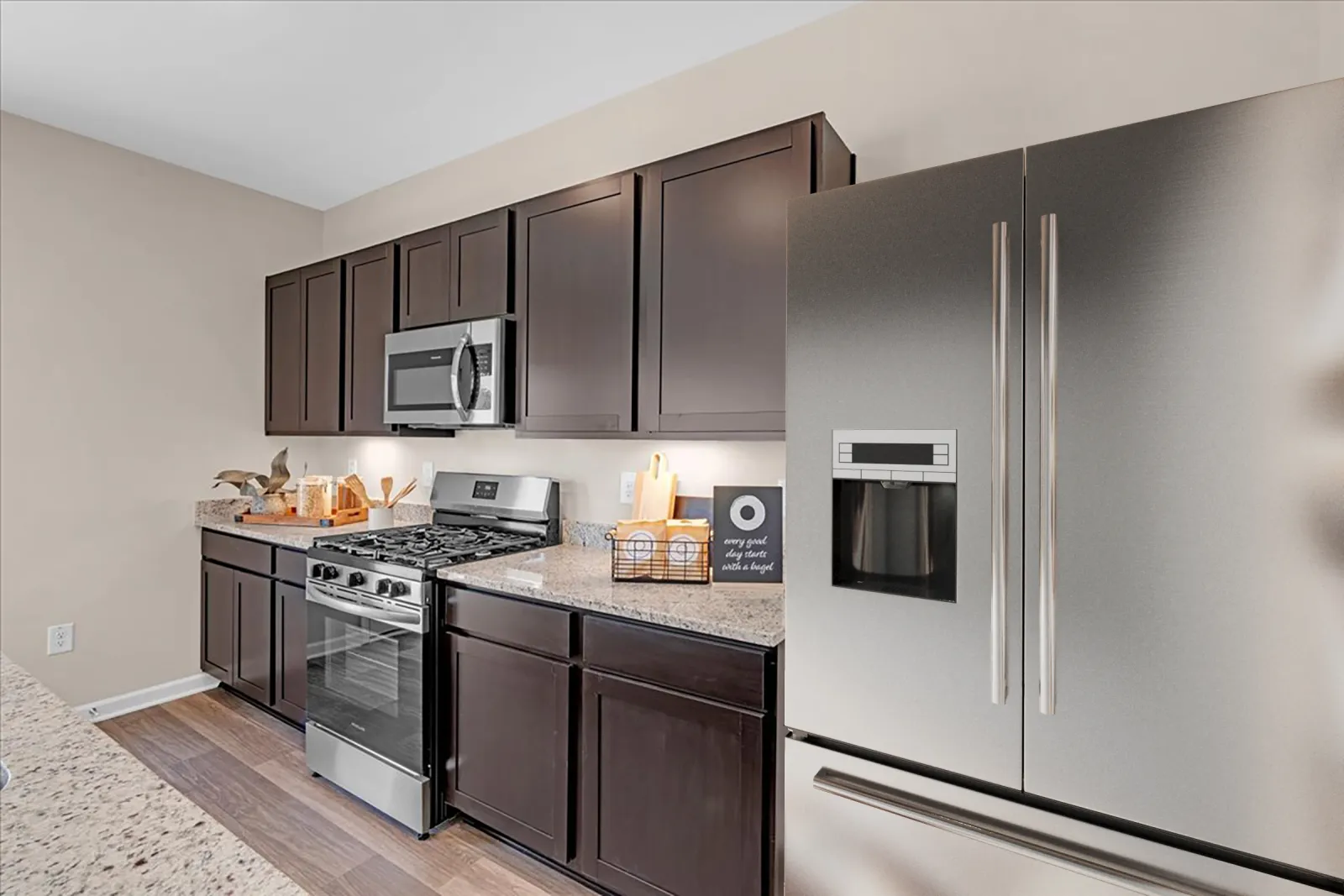 Modern kitchen with stainless steel appliances and dark wood cabinets, featuring a granite countertop.