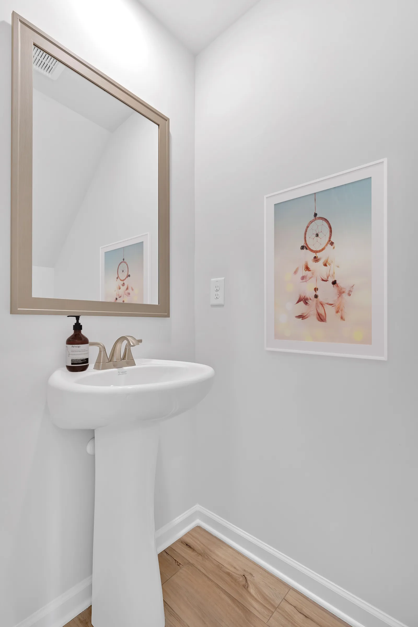 Modern bathroom with elegant sink, decorative mirror, and a dreamy dreamcatcher print.