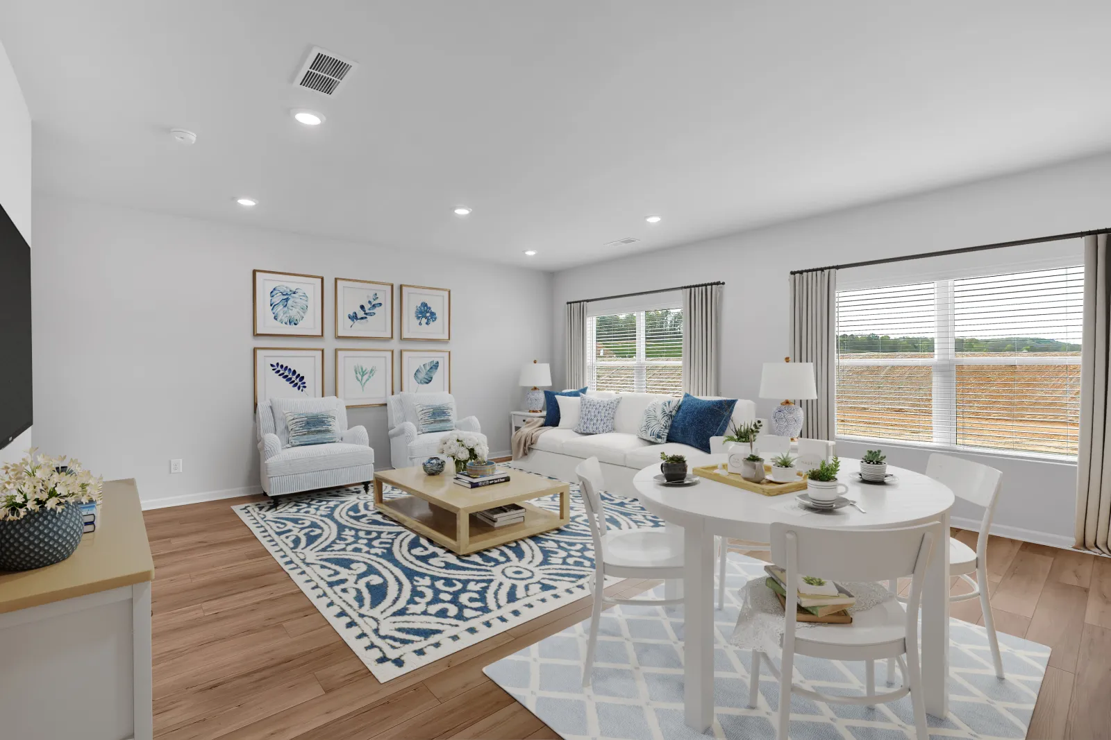 Bright and stylish living room with blue accents, white furniture, and large windows for natural light.