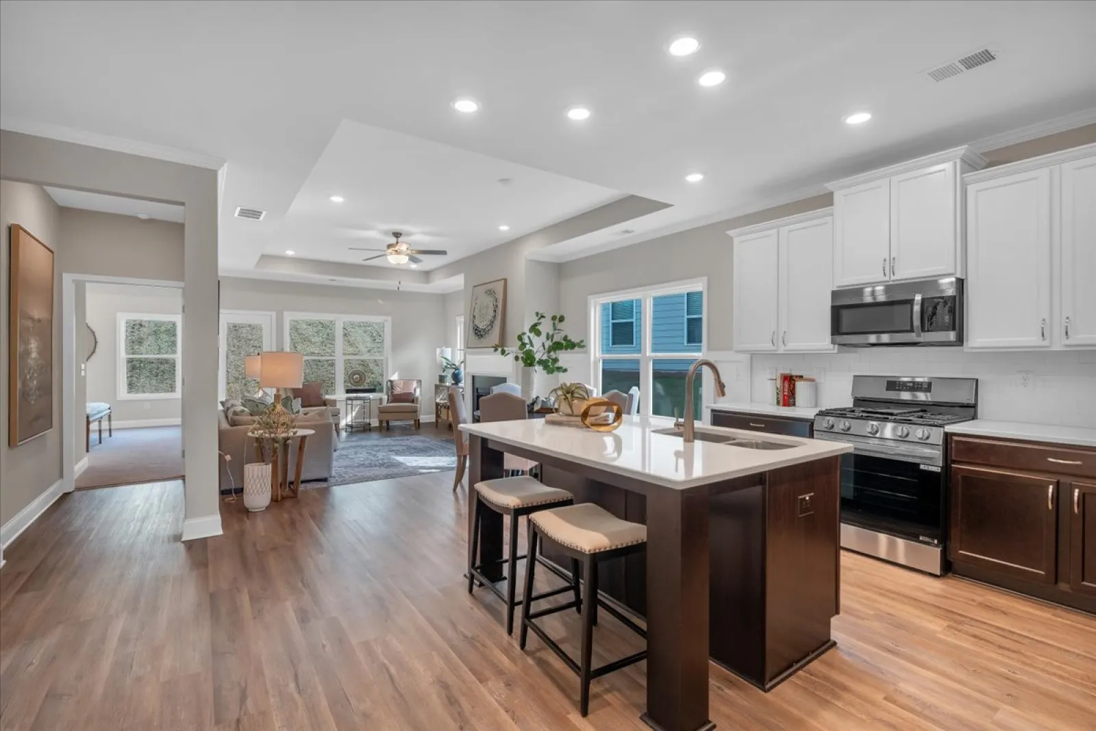 Bright modern open kitchen with island, stools, stainless steel appliances, and adjoining living room with seating area.