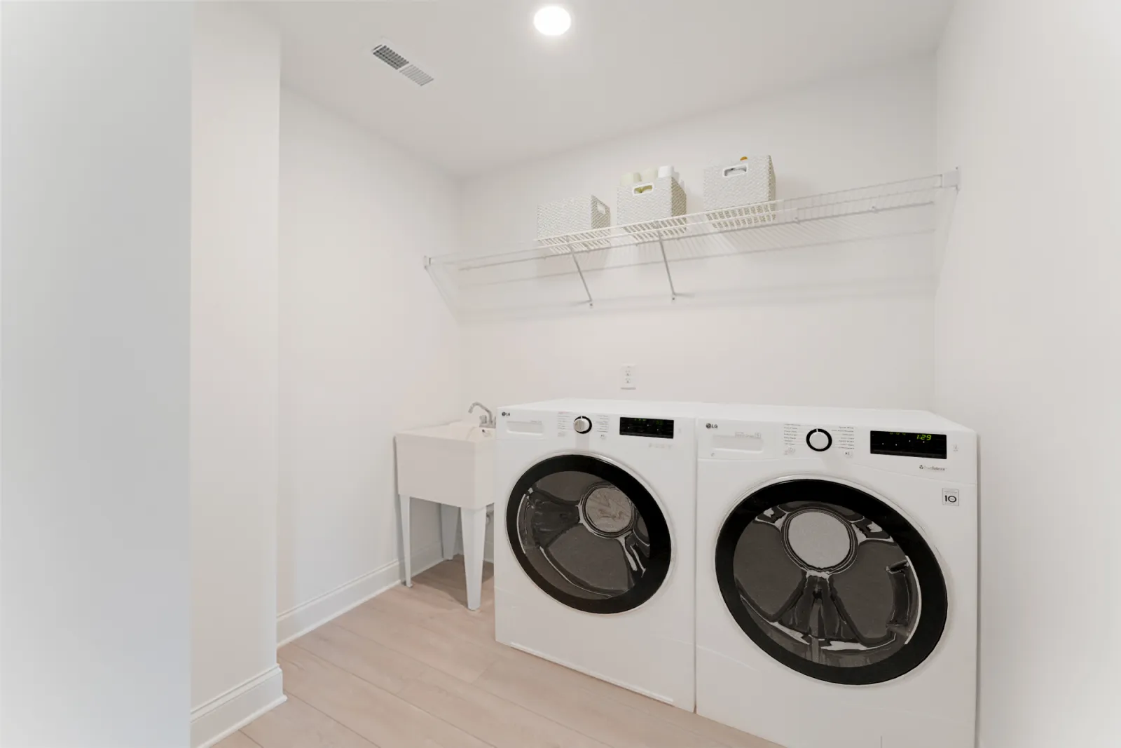 a white laundry room with a white shelf and a white wall