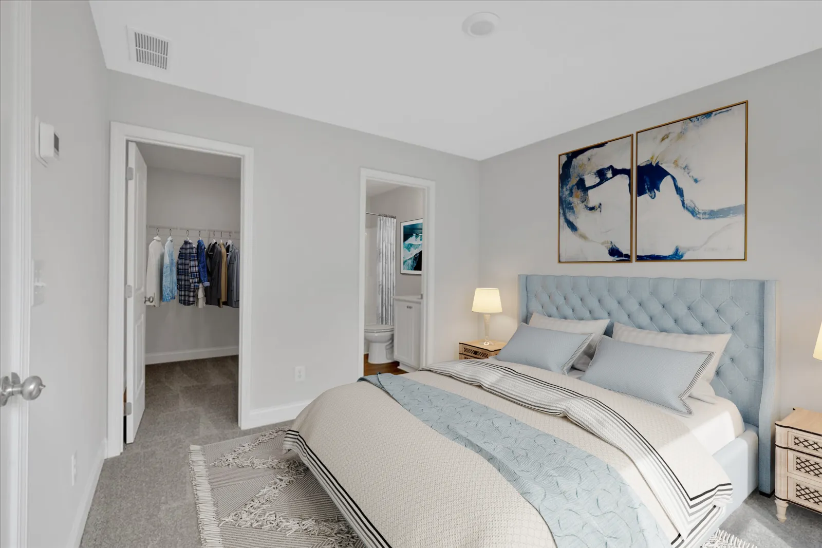 Modern bedroom with light blue tufted headboard, cozy bedding, abstract art, and entrances to closet and bathroom
