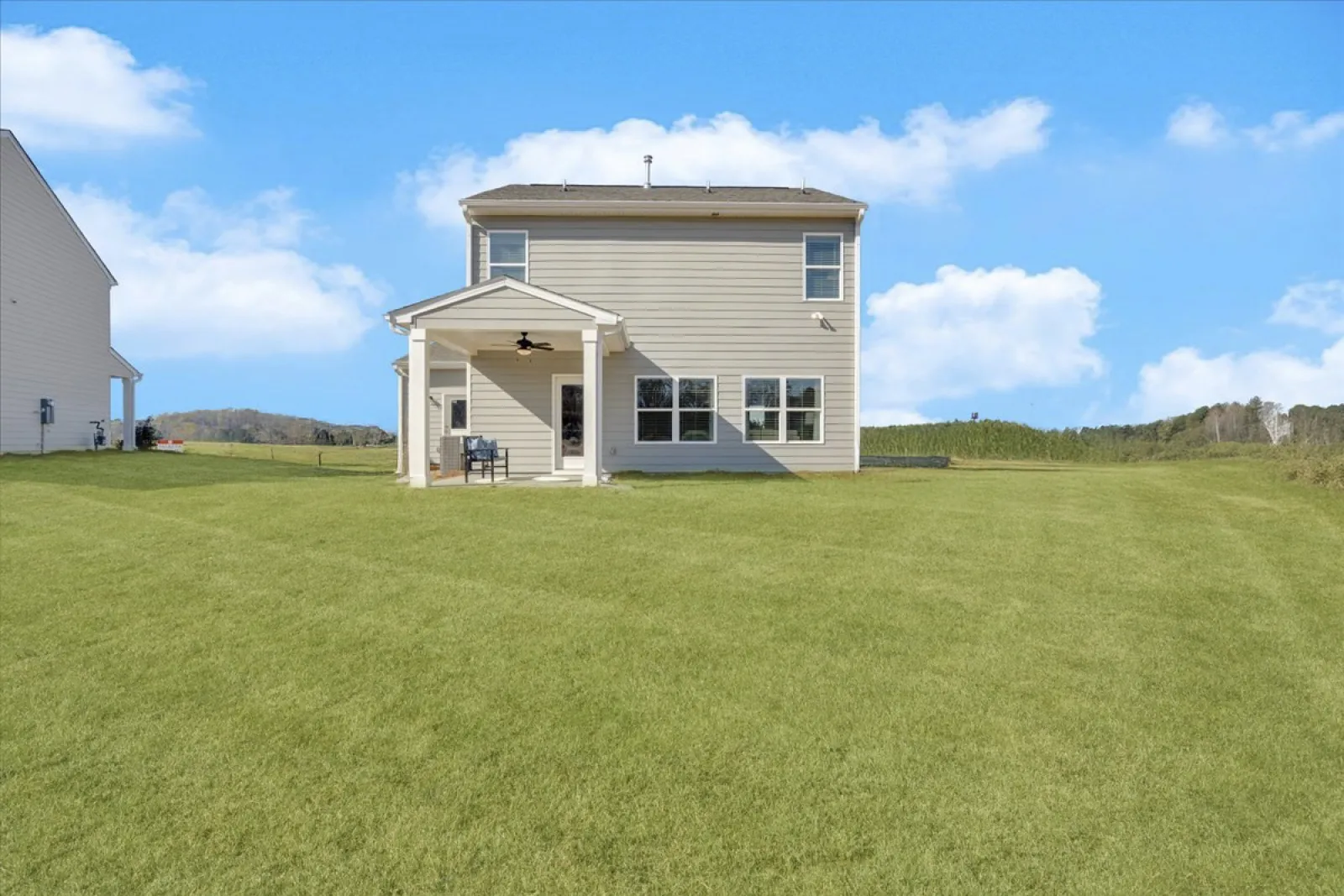 Spacious backyard view of a modern two-story home on a sunny day.