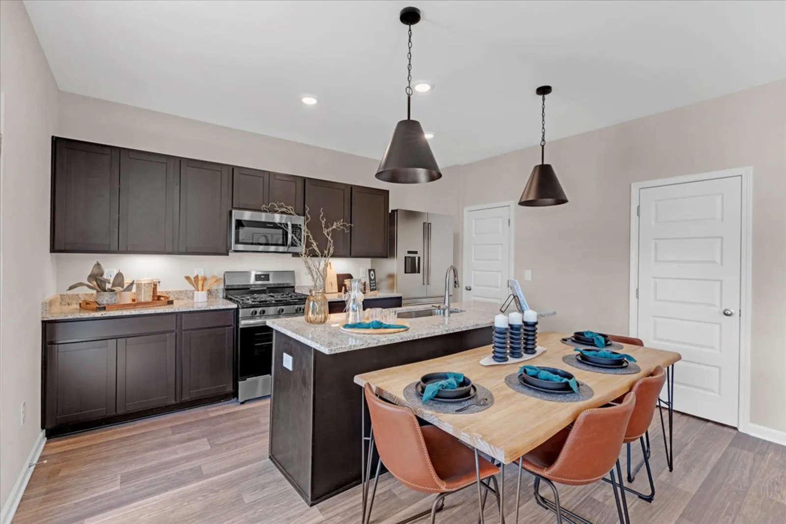 Modern kitchen with stainless steel appliances, granite countertops, and a stylish dining area featuring wood table.