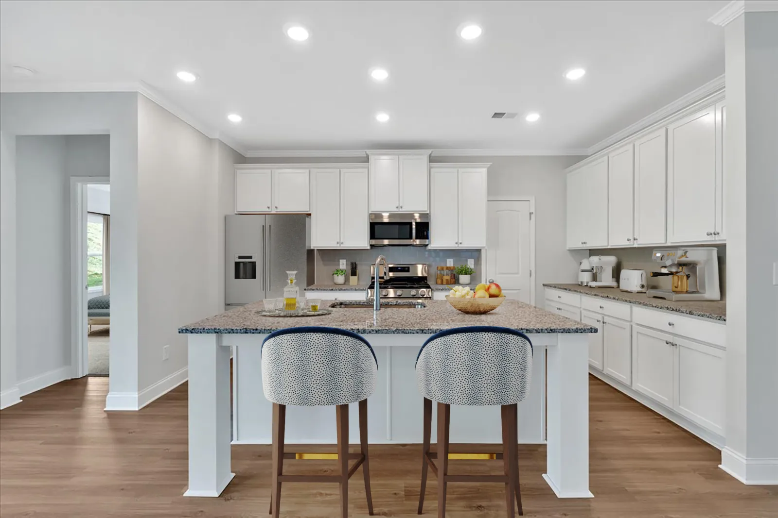 Bright modern kitchen with white cabinets, granite island, two patterned stools, stainless steel appliances, and wood floor.