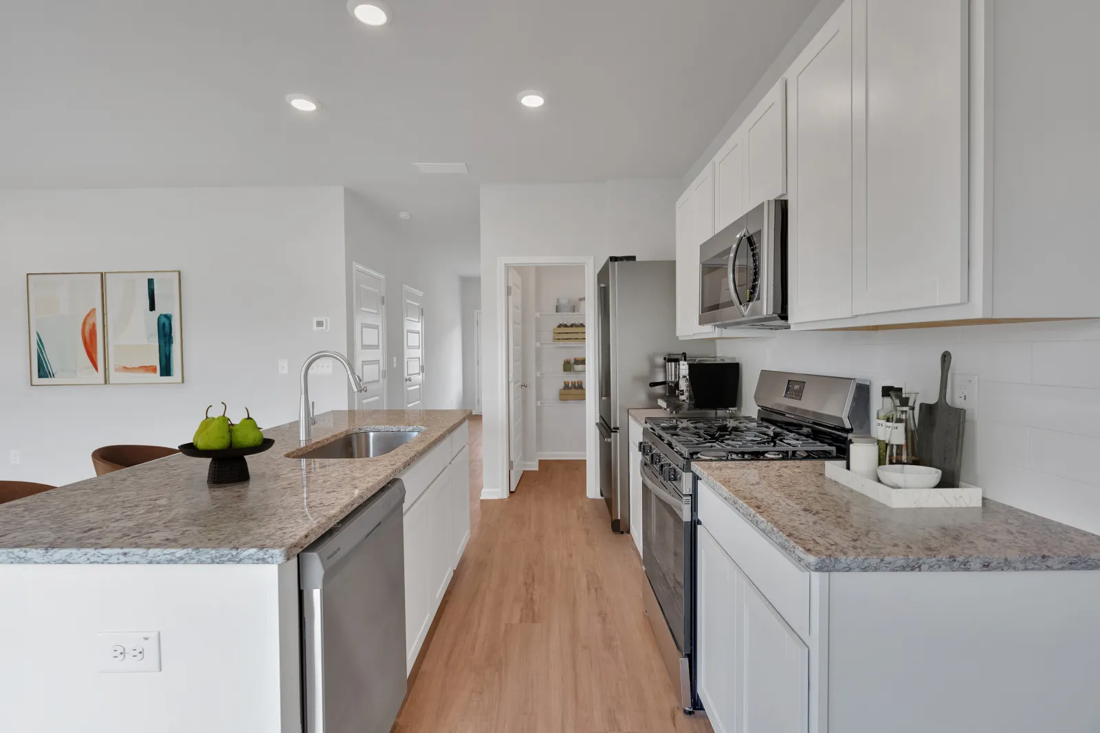 Modern kitchen with white cabinets, granite countertops, stainless steel appliances, and wood flooring