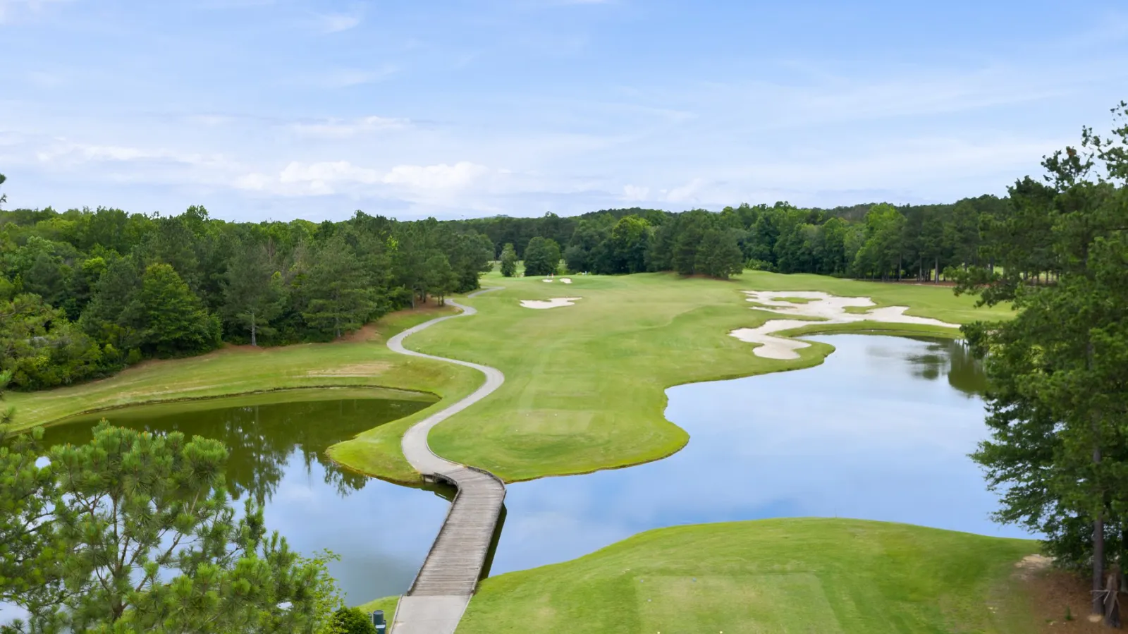 a body of water surrounded by trees and the green at The Frog