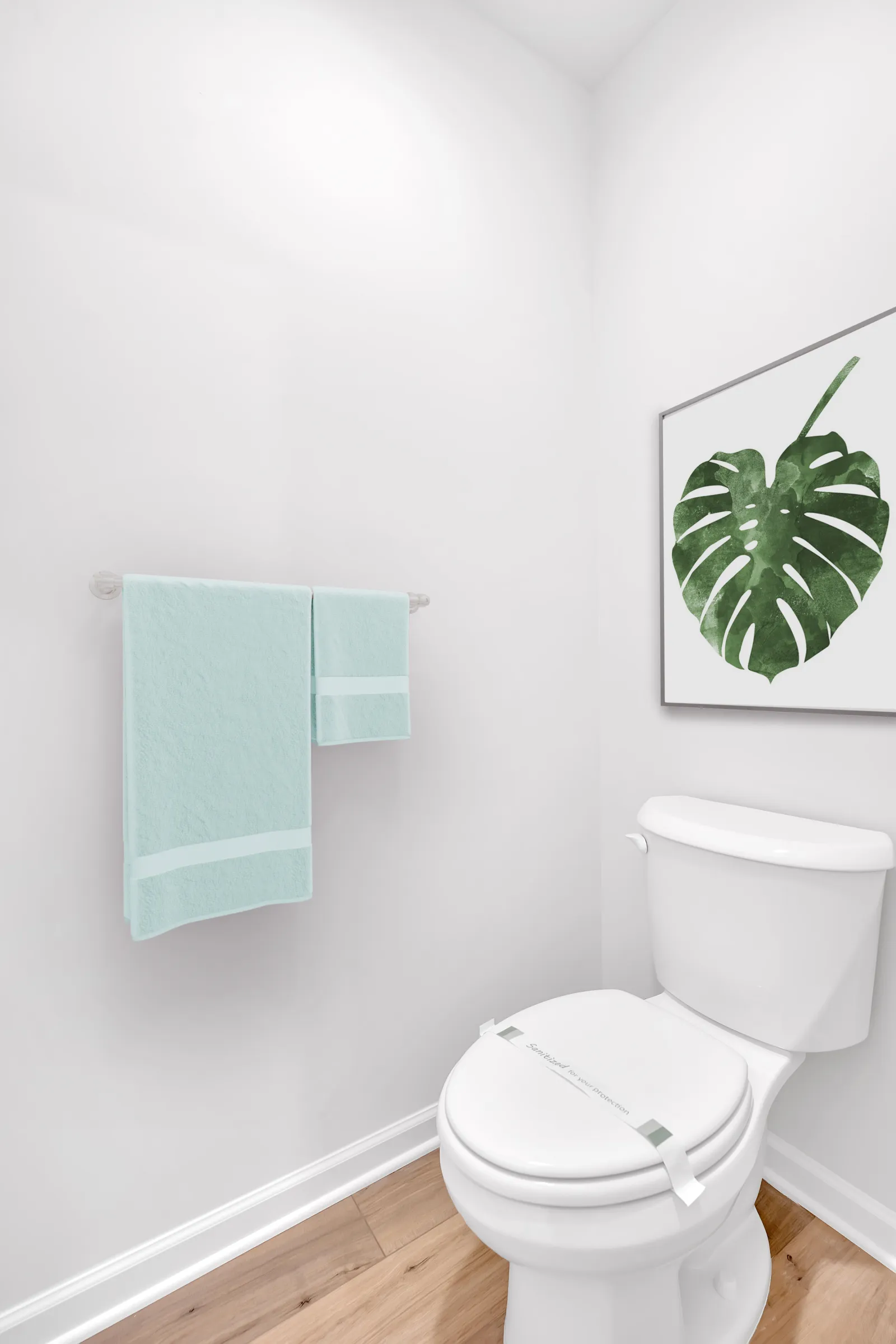 Modern bathroom with a white toilet and framed tropical leaf art on the wall.
