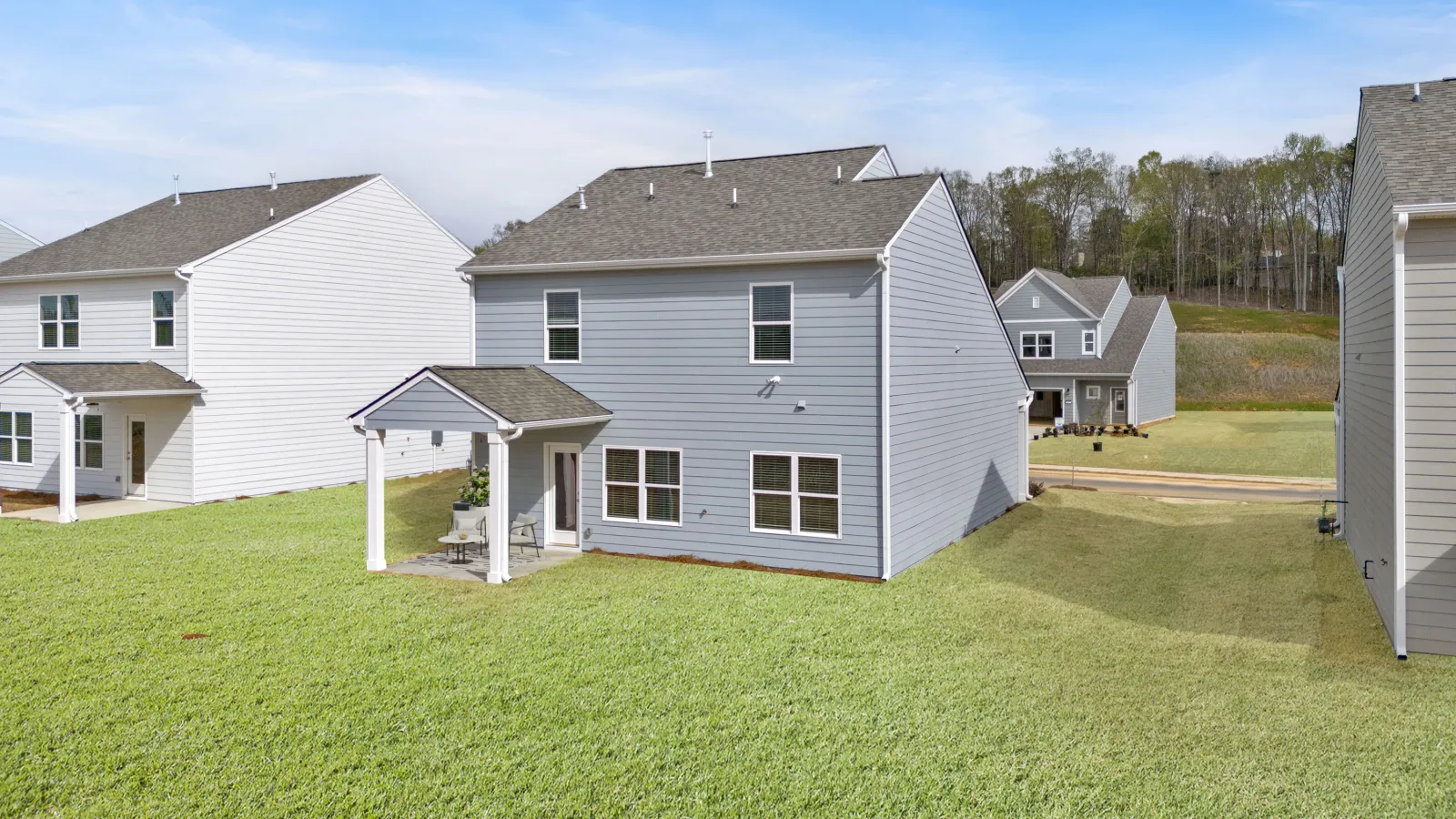 Newly built gray homes with green lawns in a residential neighborhood setting.