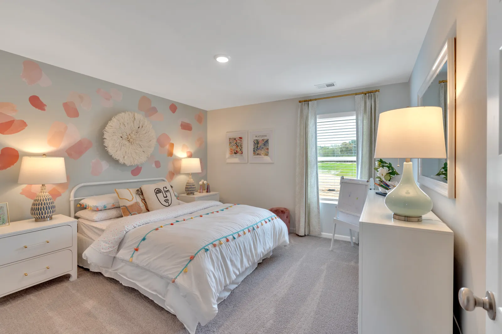 Brightly decorated bedroom with soft pastel wall art and cozy furnishings, perfect for relaxation.