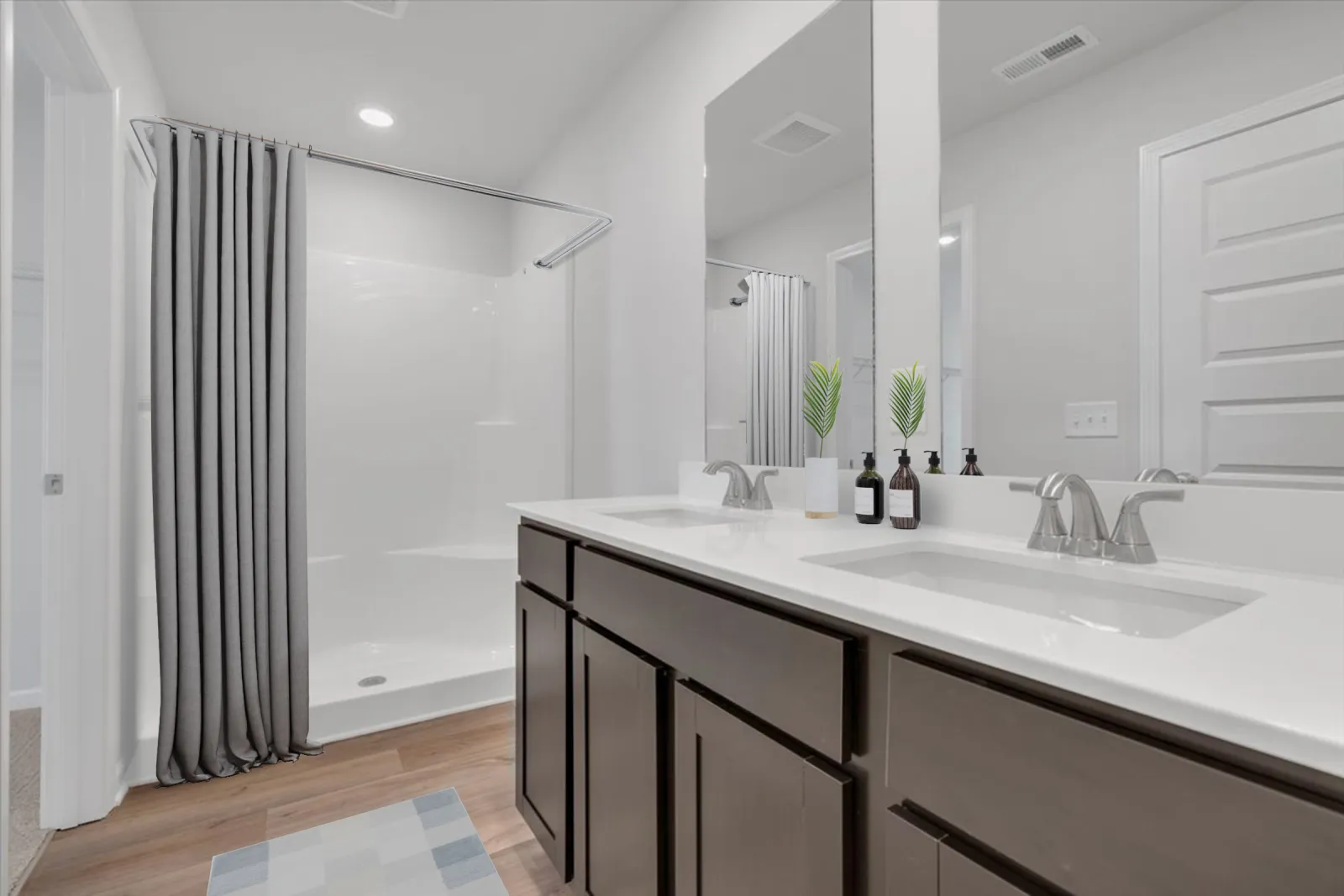 Modern bathroom with double sink vanity, dark wood cabinets, walk-in shower, gray curtain, and large mirror.