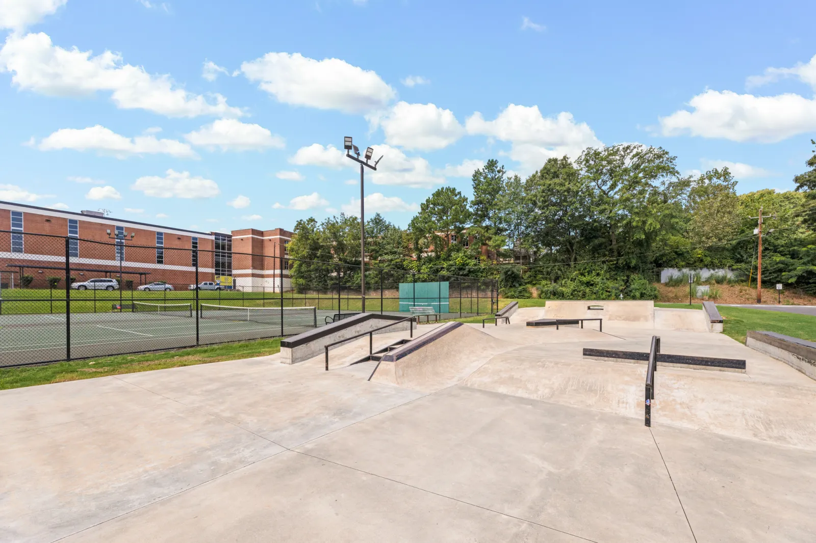 a concrete area with a fence and trees in the background