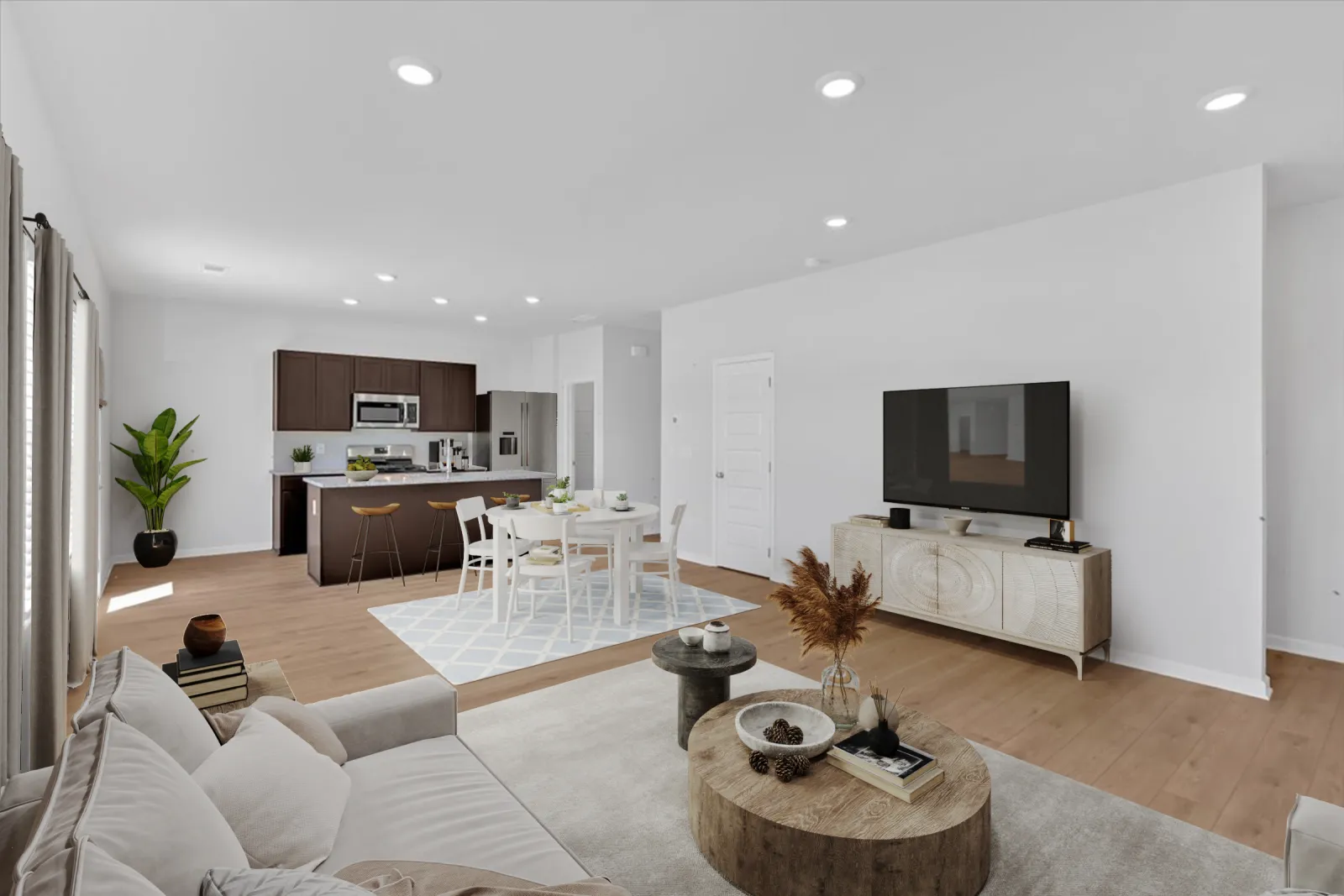 Modern open living space with beige sofa, wooden coffee table, TV stand, dining area, and dark kitchen cabinets.