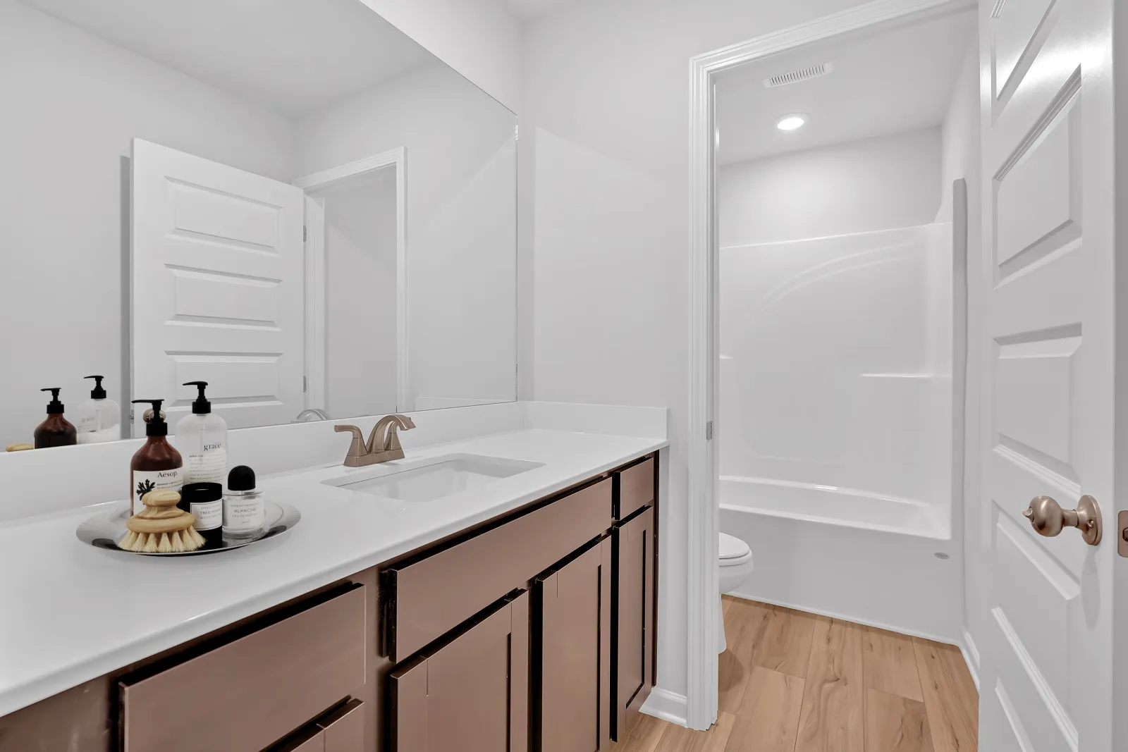 Modern bathroom featuring a white countertop, wooden cabinetry, and natural light.
