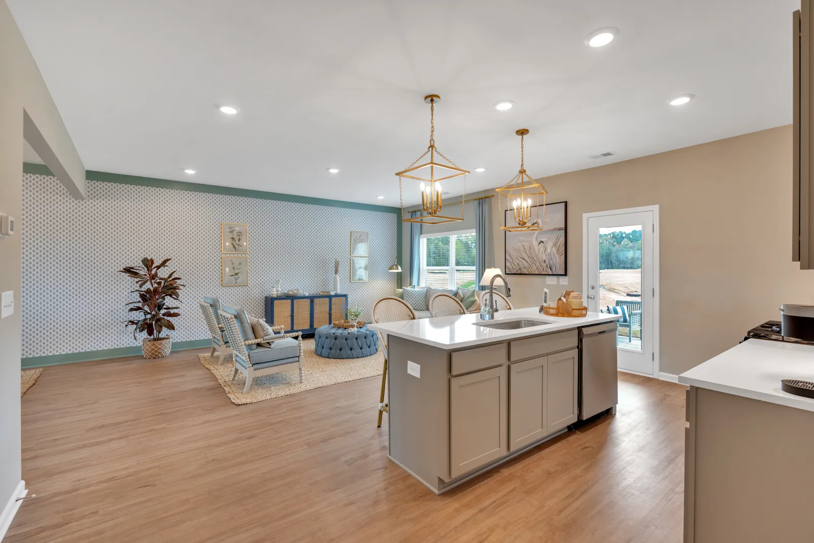 Spacious modern kitchen with wooden floors and stylish island lighting in a bright open layout.