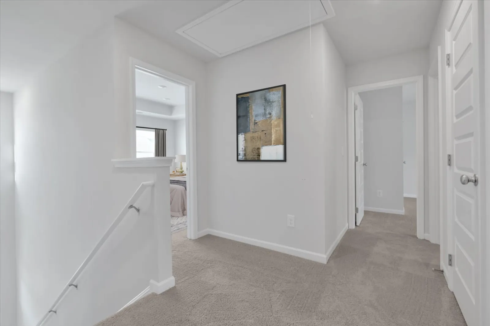 Bright hallway with beige carpet, white walls, staircase, doors, and abstract painting on wall