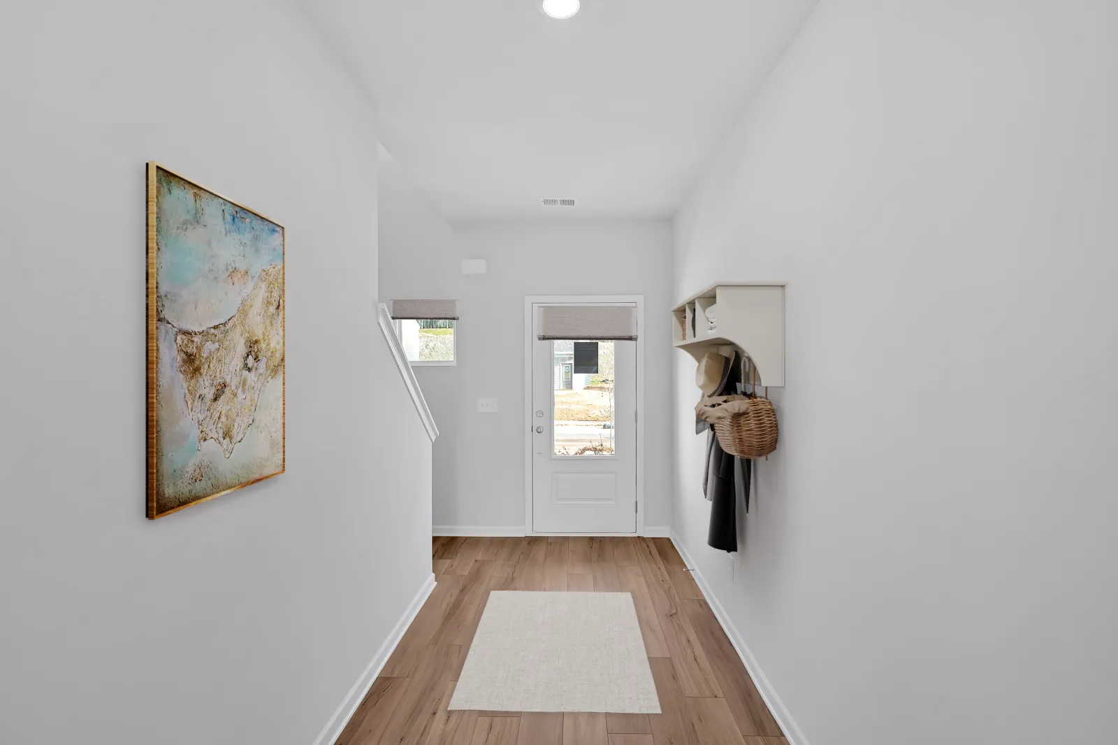 Bright and modern hallway featuring a colorful painting and a welcoming entryway.