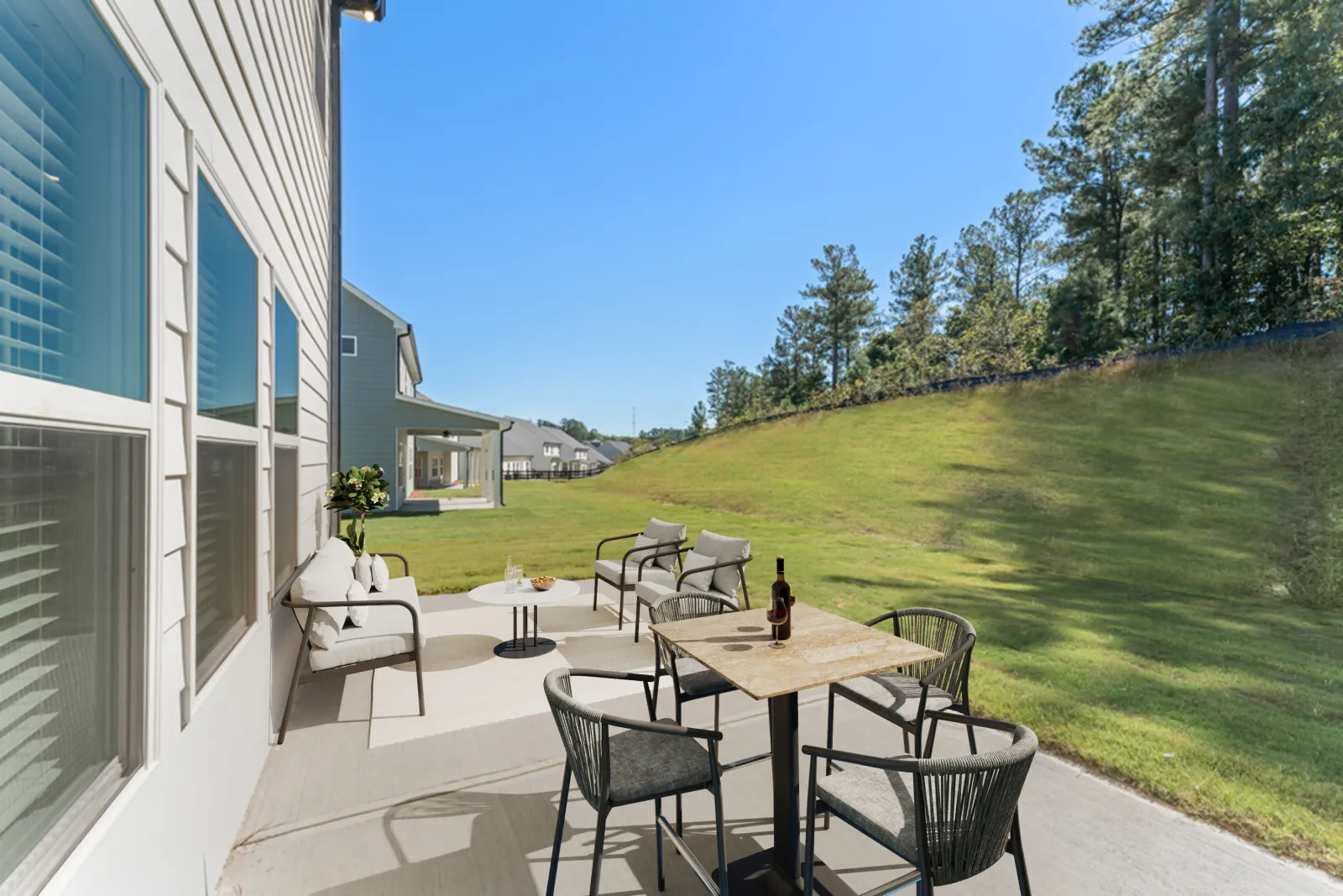 a patio with a table and chairs and a grassy yard with trees