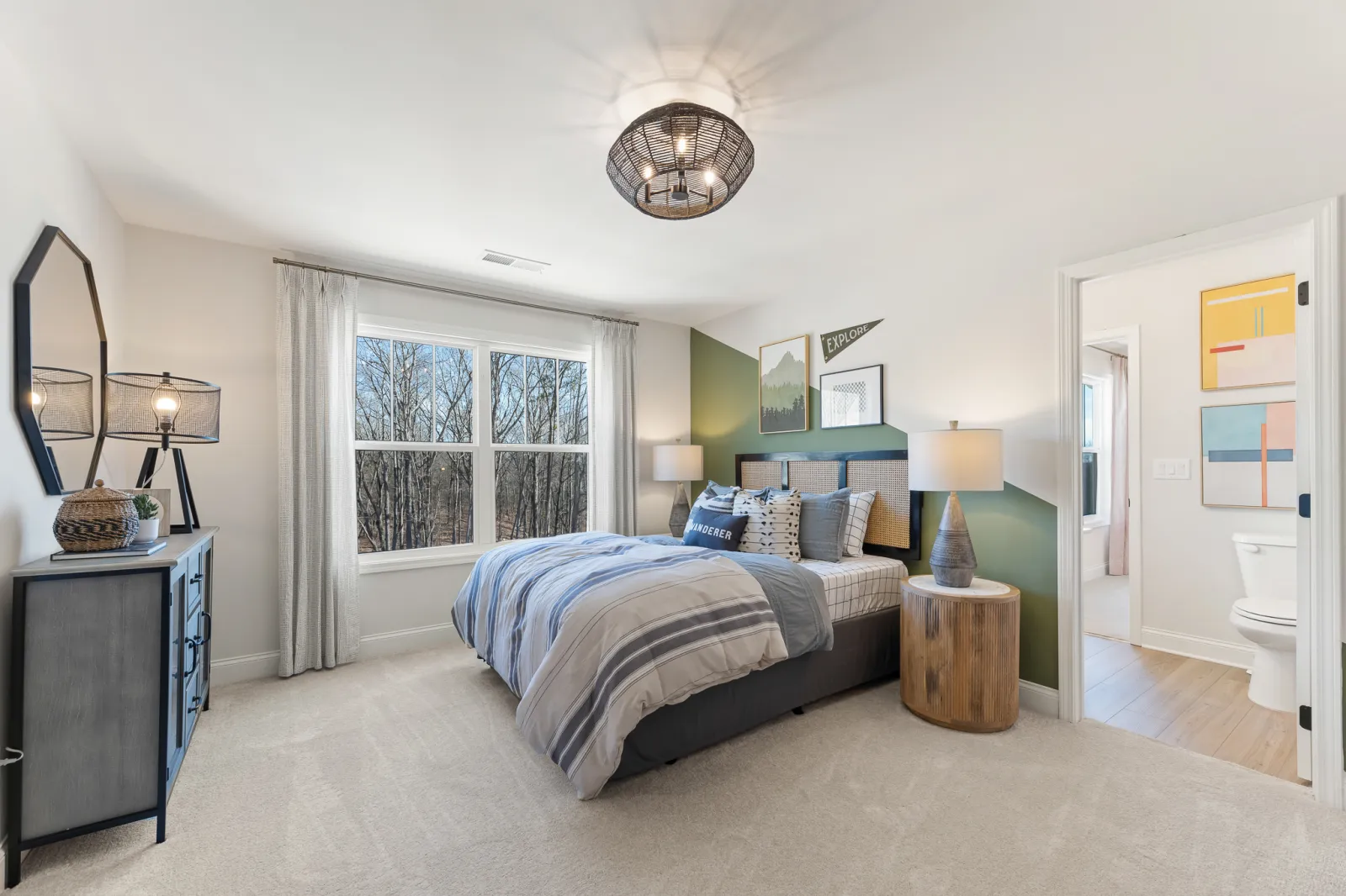 Bright modern bedroom with large window, gray bed and striped bedding, bedside lamps, and green accent wall.